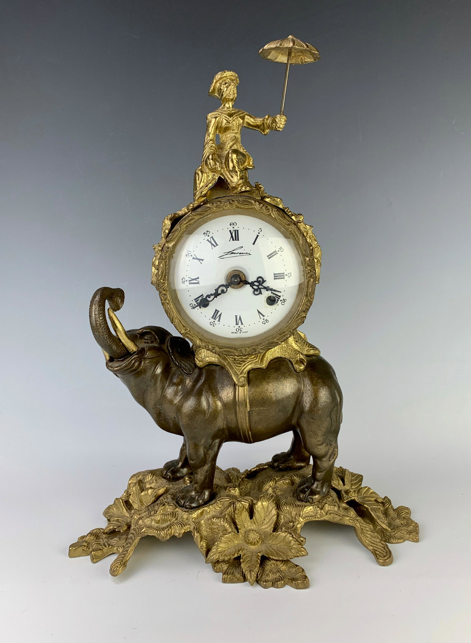 Italian Chinoiserie Bronze Elephant Clock: Bronze mantle shelf clock in the form of an elephant with its trunk up, having a clock on its back with an Asian man sitting atop with umbrella, movement made in Germany, comes with key, movement and 