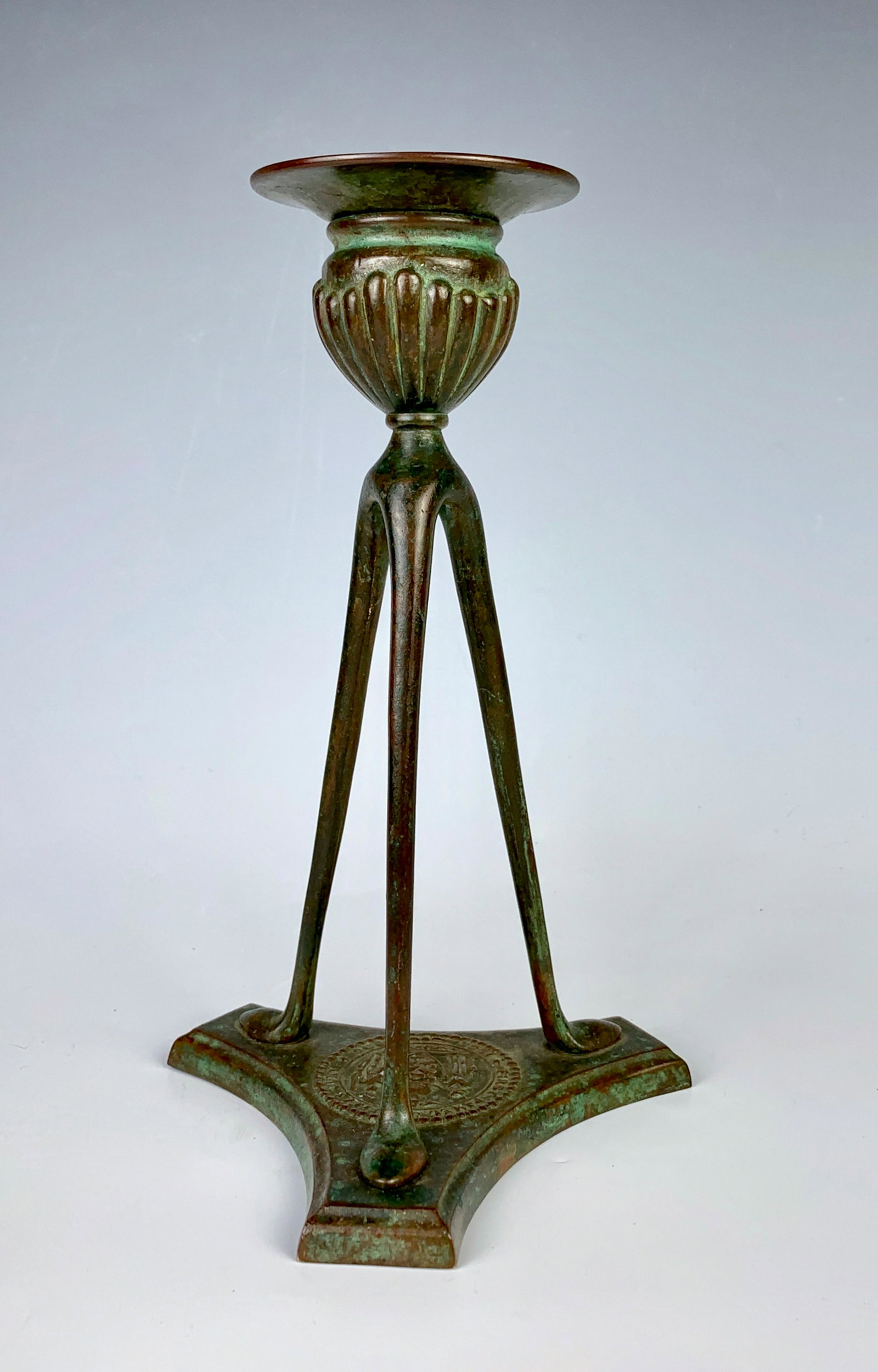 Tiffany Studios Candlestick: Circa 1900, a bronze candlestick having three slender supports and a tricorner base which has a circular raised seal that reads "First Panel Sheriff's Jury 1905-1906", signed "Tiffany Studios New York
