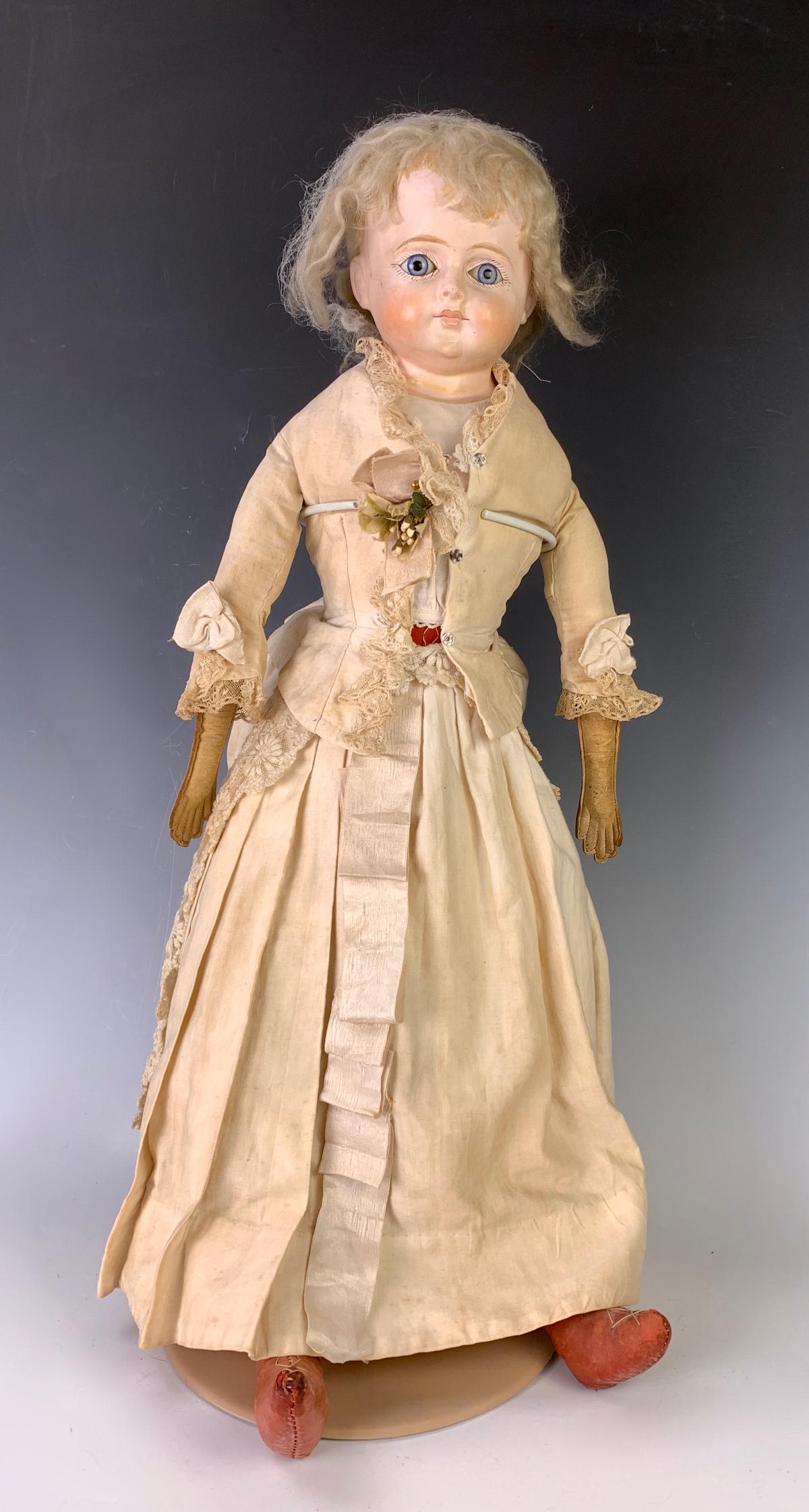 26" German Papier Mache Shoulderhead Lady: C. 1860, "Patent Washable", blue glass eyes, original blond mohair wig, closed and outlined mouth, cloth body with leather arms, red cloth lower legs, red leather boots with gold tassels sewn on, prov