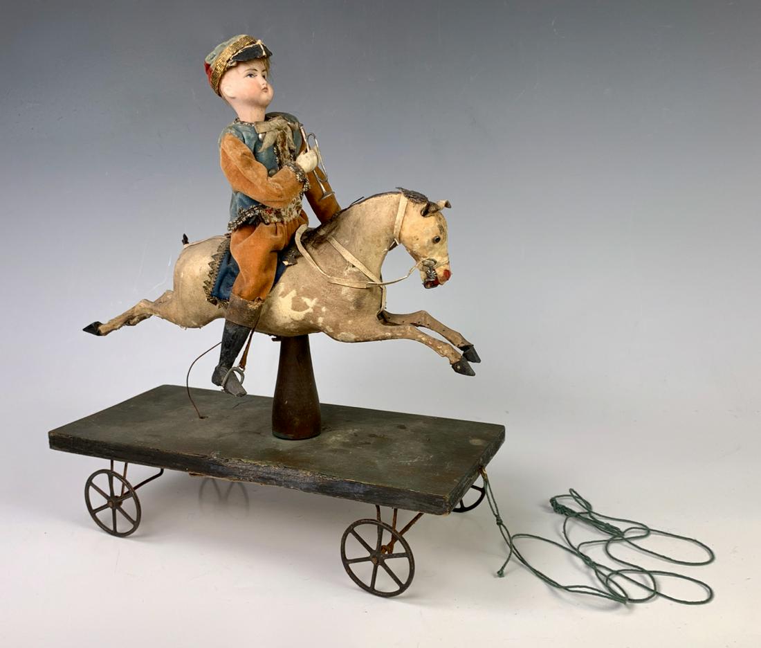 Antique "Soldier on Horse" Pull Toy c. 1880: Wonderful antique pull toy of a soldier on a horse, when pulled the rear wheels turns bellows underneath which activates the soldier's arms to blow the horn, bellows need work, horse tail missing, 12"
