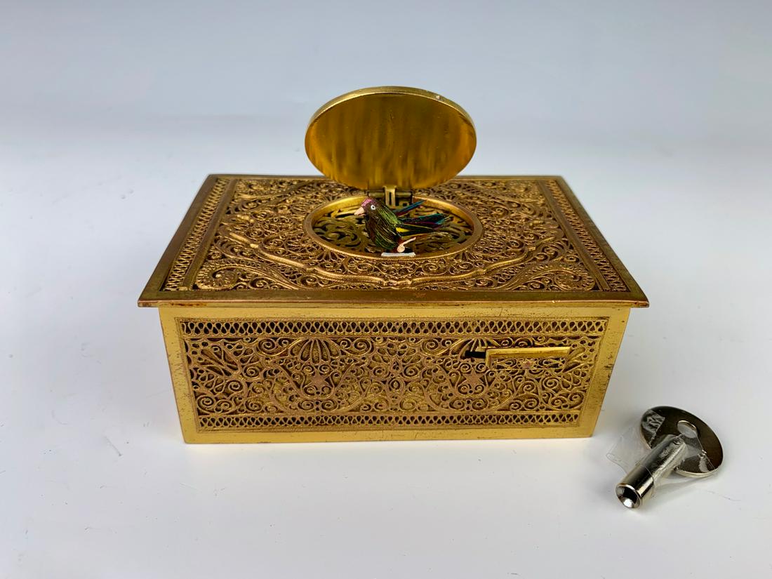 Singing Bird Box with Ornate Gilt Bronze Case: Most likely made by Karl Griesbaum, having a switch on front that activates a singing bird, comes with key, marked "Made in Germany", very good condition, 4" x 2.5" x 1.5" Note: Visit our website to s