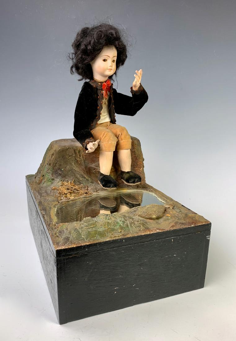 Antique Automaton "Admiration" Music Box c. 1880: Having a young boy sitting on rocks admiring himself in both his reflection in water or looking into a missing mirror, when wound his arms are in movement, has bisque head, good condition, working con