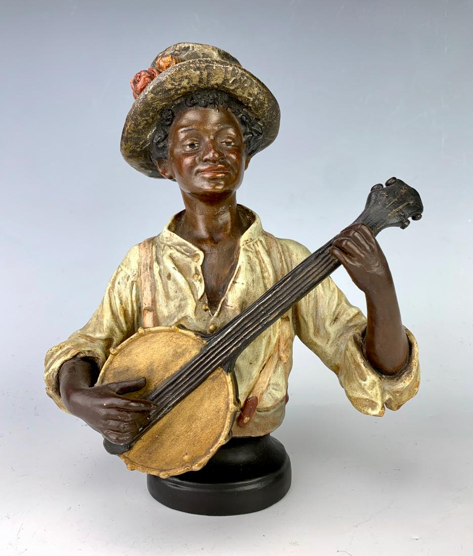 Black Americana Banjo Player C. 1900: Most likely made in Austria of terra cotta of a black boy playing a banjo, numbered "3406", good condition, end of banjo has old repair, 8.25" height **Lifetime estate collection of Jeannine Hamilton,