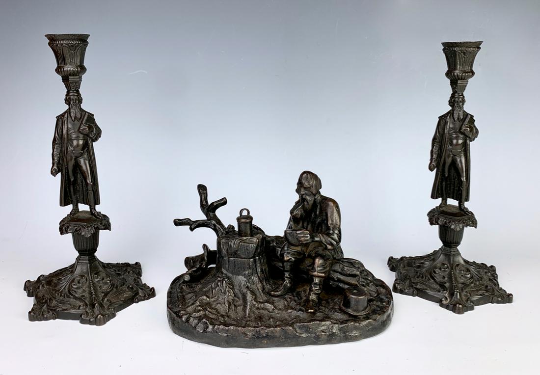 Imperial Russian Iron Inkwell & Candlesticks: Depicting a bearded man sitting on a tree log while eating, tree stump lifts up to reveal inkwell with original insert, branches act as a pen holder, comes with a pair of cast iron figural candlestick