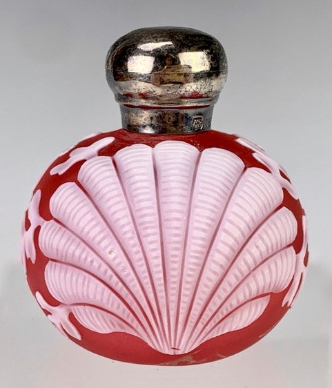 English Cameo White Clam Over Red Glass Bottle: Perfume bottle having a red glass ground with cameo white clam shells and hallmarked sterling top, tiny dings to silver top, 2.25" height