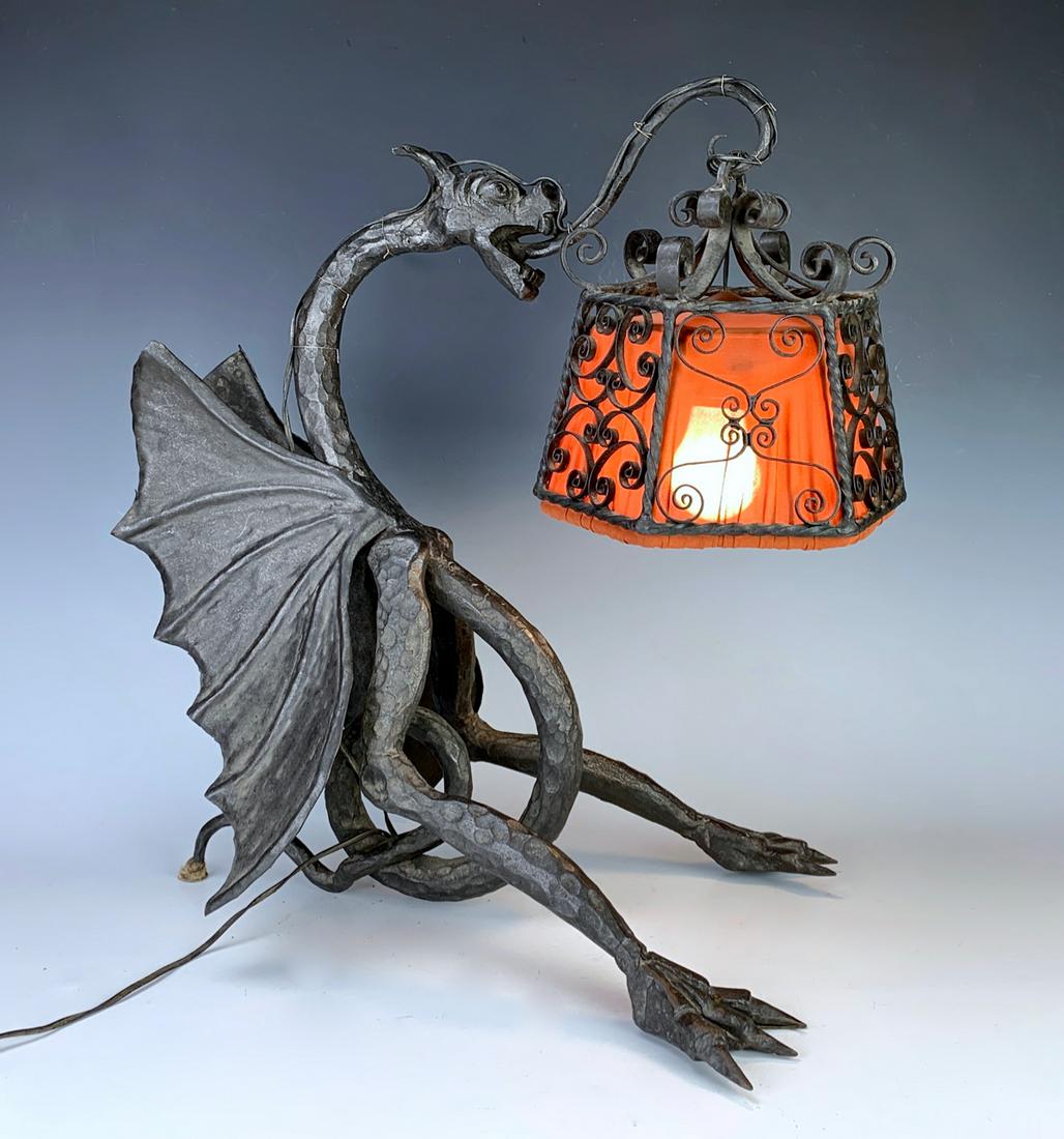 C. 1920's Spanish Wrought Iron Winged Dragon Lamp: Stunning wrought iron winged dragon table lamp, made in Spain, hanging from dragon's tongue is a gothic style iron shade with an orange material covering, very good condition, has European socket and