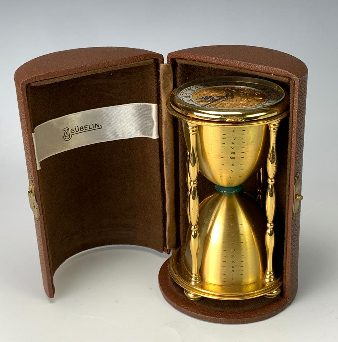 Gubelin Brass Hourglass Form Clock: 20th century, with engraved brass dial with Roman numerals, comes with leather fitted case, jade ring in the center of hourglass, in fine running condition at time of auction, 5.25" x 3" *Clocks and w
