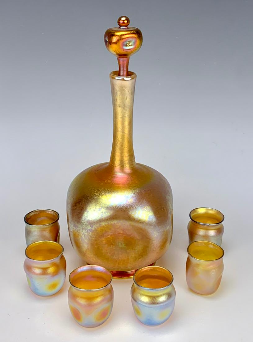 Sgd L.C. Tiffany Favrile Decanter & 6 Glasses: Gold favrile liquor set consisting of a decanter with pinched in sides and 6 shot glasses, signed "L.C. Tiffany Favrile 349", very good condition, 10" tallest