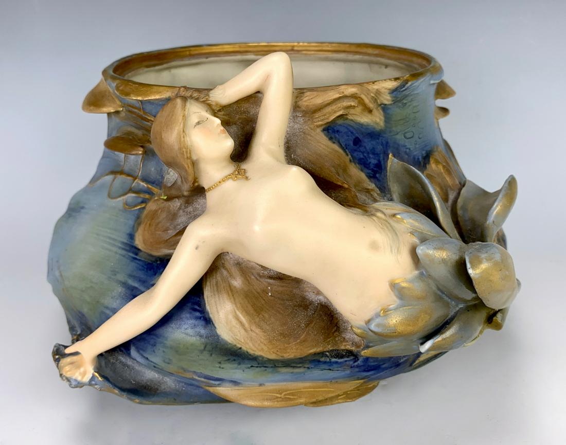 Amphora Art Nouveau Vase w/ Emerging Nude C.1890: Vase with nude emerging from a flower on the side and water lilies surrounding the vase, fabulous colors of blue and green with gilt highlights, she is done with flesh tones, marked with "Amphora" ins
