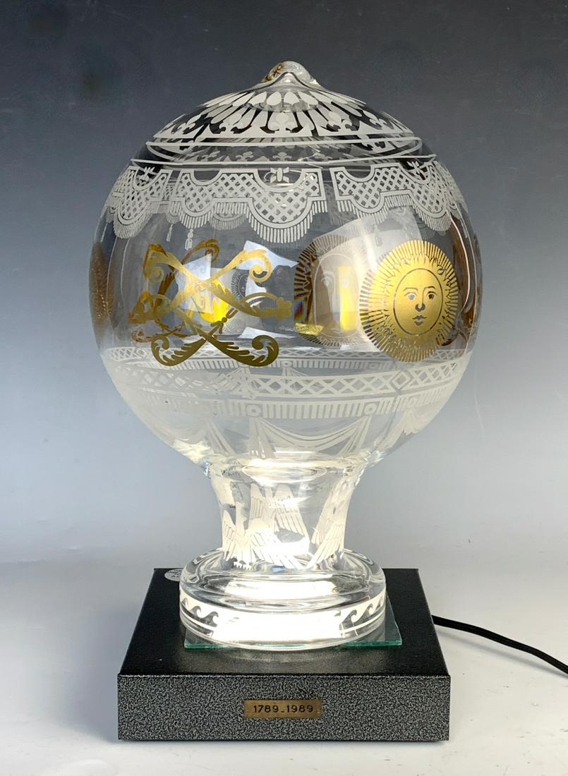 Daum France Hot Air Crystal Balloon Lamp: Having a crystal glass hot air balloon shaped shade decorated with sun faces, eagles sit atop a metal luminaire base, base signed "Daum" and shade is signed "Daum France", good condition, shade 12.5"