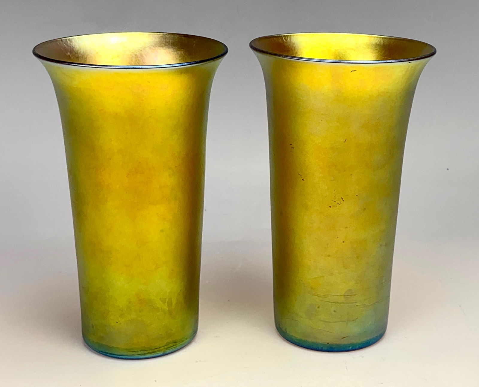 Pair of Steuben Aurene Tumblers: Both signed "Aurene Haviland & Co". Cylindrical shape with flared rims in gold iridescence. 6" each. Condition: Very Good.