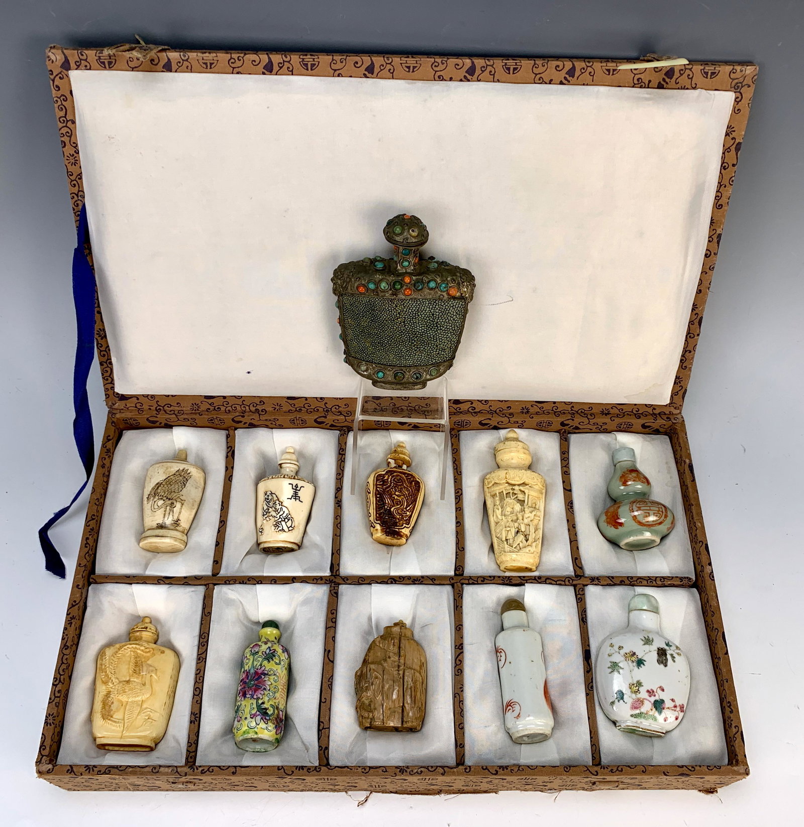 Collection of 11 Chinese Snuff Bottles: Consists of a box set of 10 porcelain and bone carved snuff bottles, 3 signed, with a snuff bottle having colored stones and pewter body, one with chip at neck, one minor chipping on base, one missing