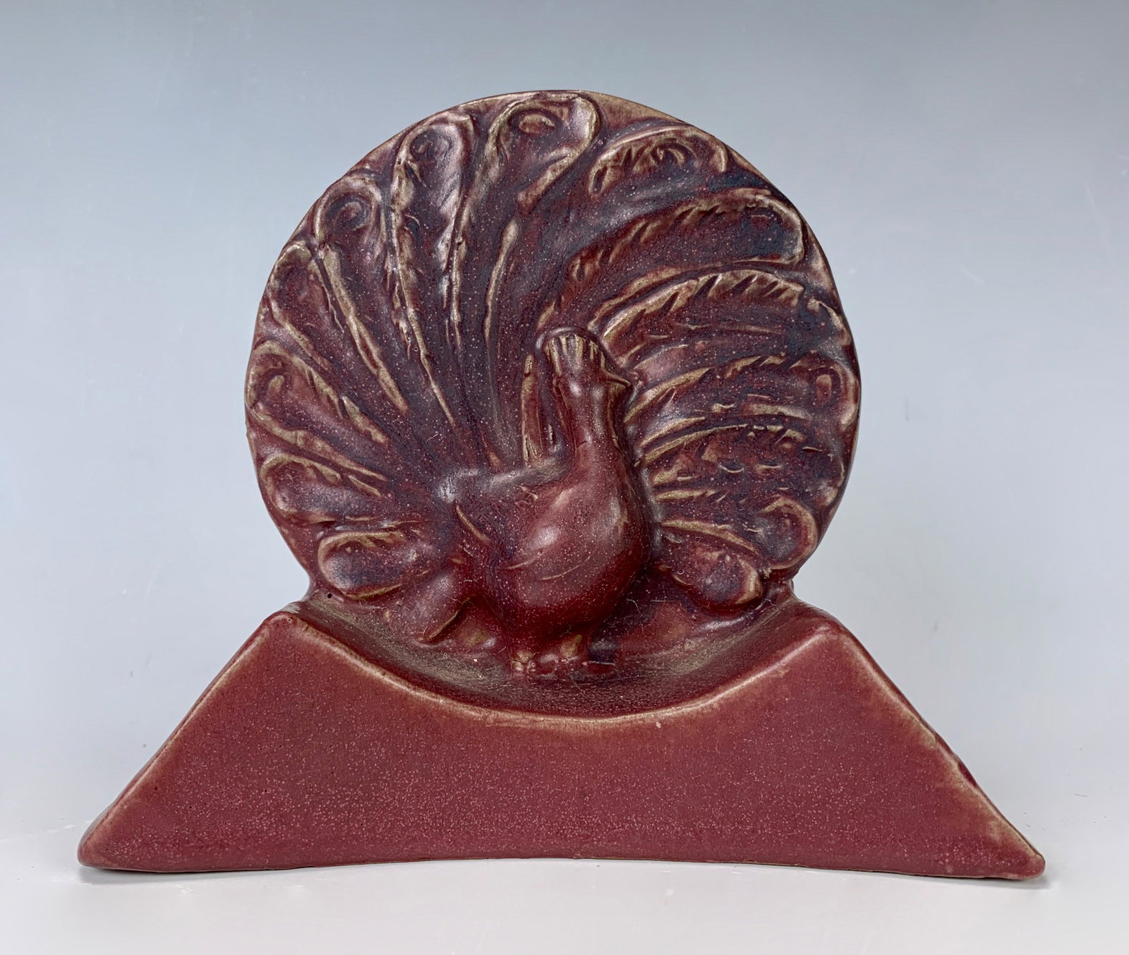 Van Briggle Peacock Bookend Dated 1915: Fine early example of an early Van Briggle peacock bookend with deep maroon color, Van Briggle logo and "1915" on bottom with a mark next to logo (possibly artist mark), very good condition, 5.25" x 5
