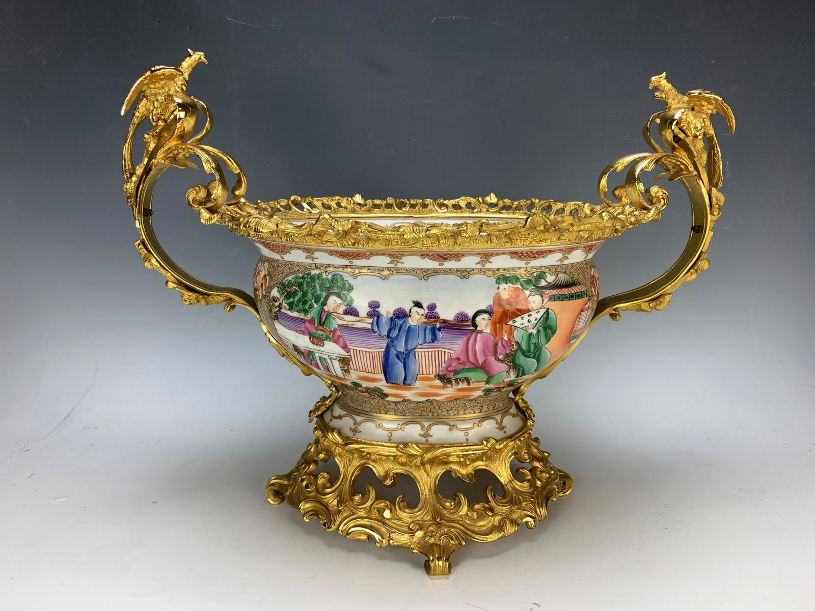 Chinese Porcelain & Gilt Bronze Centerpiece: Deep oval decorated bowl with gilt bronze Rococo mounts, cartouche scenes with Chinese figures, each end with winged bird, spider web mark on interior, 13.5" x 18"