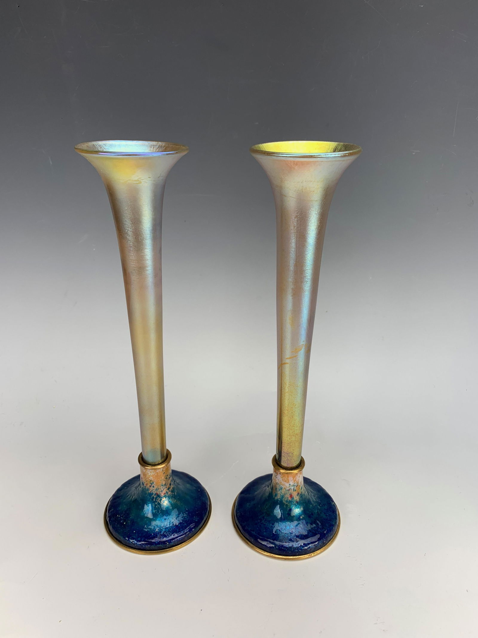 Pair Tiffany Favrile & Enamel Vases: Rare to find, a matched pair of Tiffany Studios gold favrile iridescent art glass vases mounted into matched blue enamel bases, bases signed "Louis C Tiffany Furnaces, Inc" logo, favrile vases have me