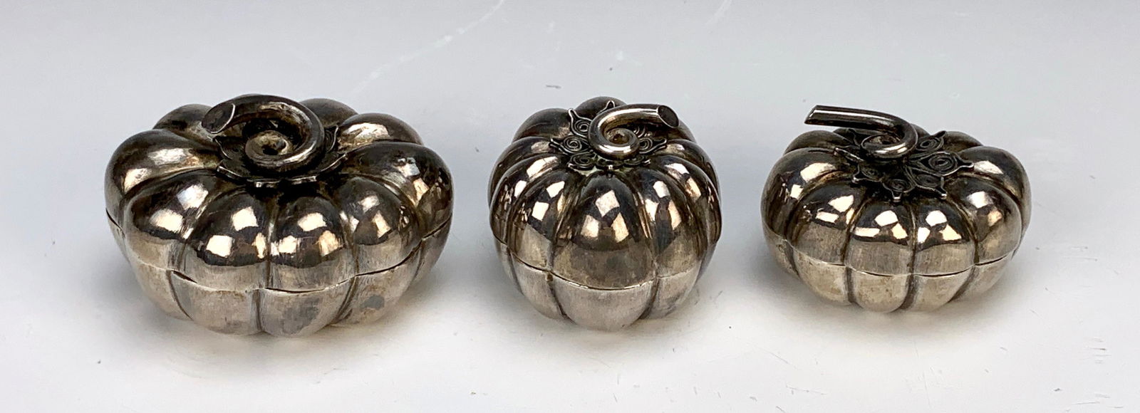 Set of 3 'Pumpkin' Sterling Pill Boxes.: Two oval shaped sterling silver pill boxes, both marked 925, one round pillbox is unmarked. Largest is 2" and total weight of set is 80 grams.
