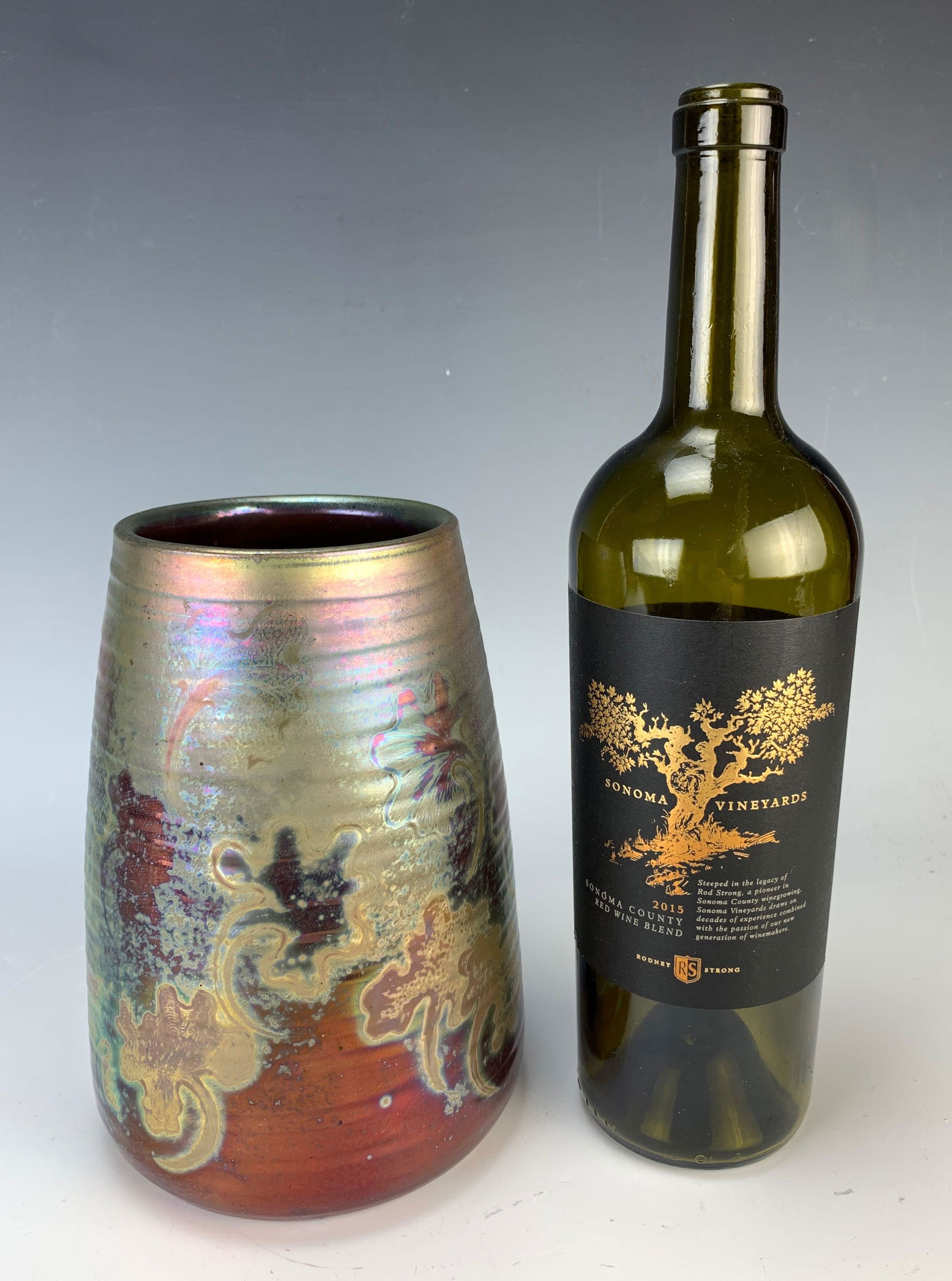 Clement Massier (1844 - 1917) Iridescent Vase: Having a larger iridescent vase decorated with leaves and flowers, in colors of red, green, silver and gold highlights. Signed Clement Massier, golfe Juan Am. Size: 7.75" tall. Very good condition.