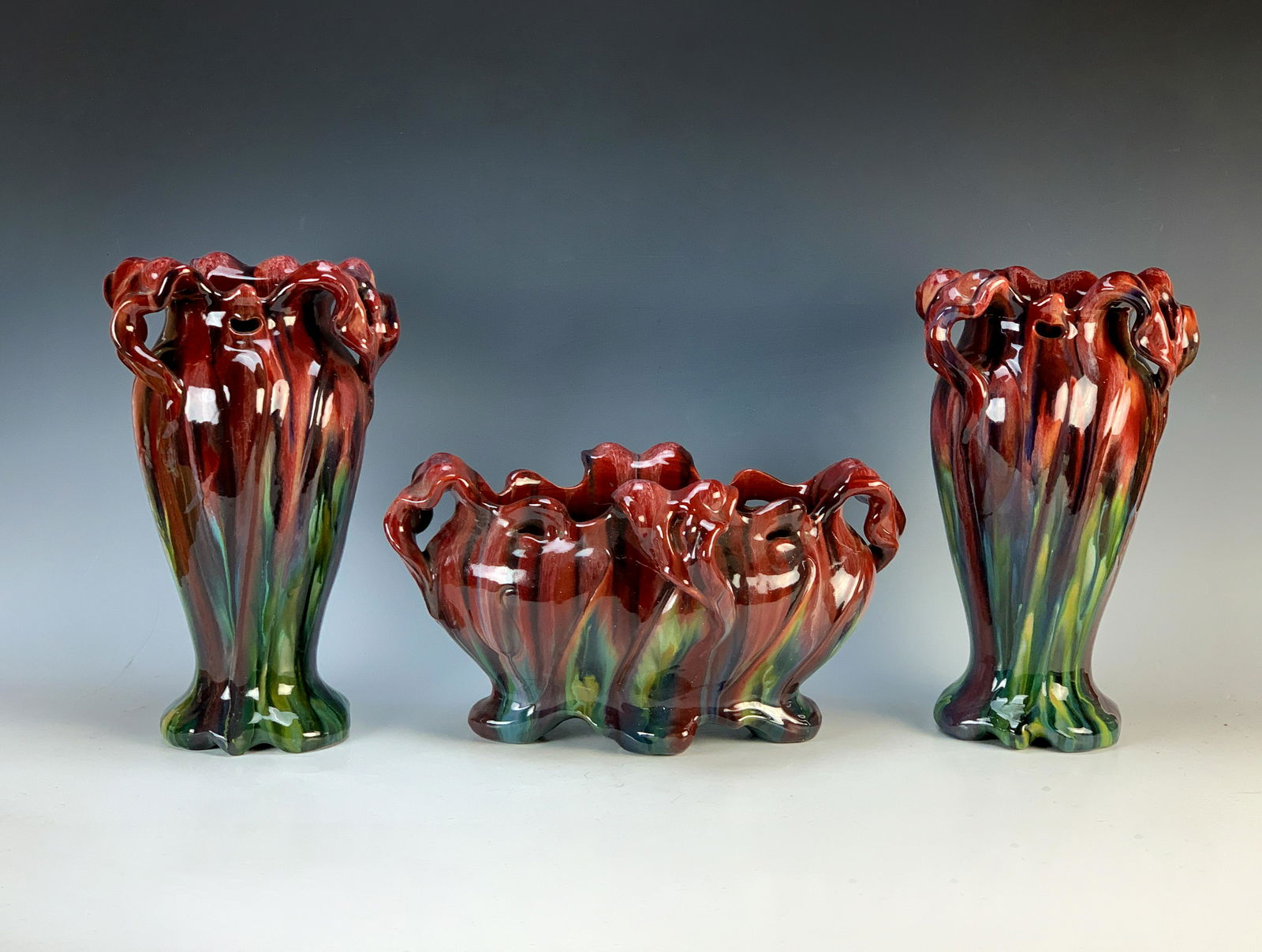 Jerome Massier (1850-1916) 3 Piece Art Nouveau Set: Great 3 piece Art Nouveau red glaze pottery fireplace mantle set. Each signed Jerome Massier, Vallauris France. Having 2 vases and center bowl in colors of reds with darker streaks of red down to a gr