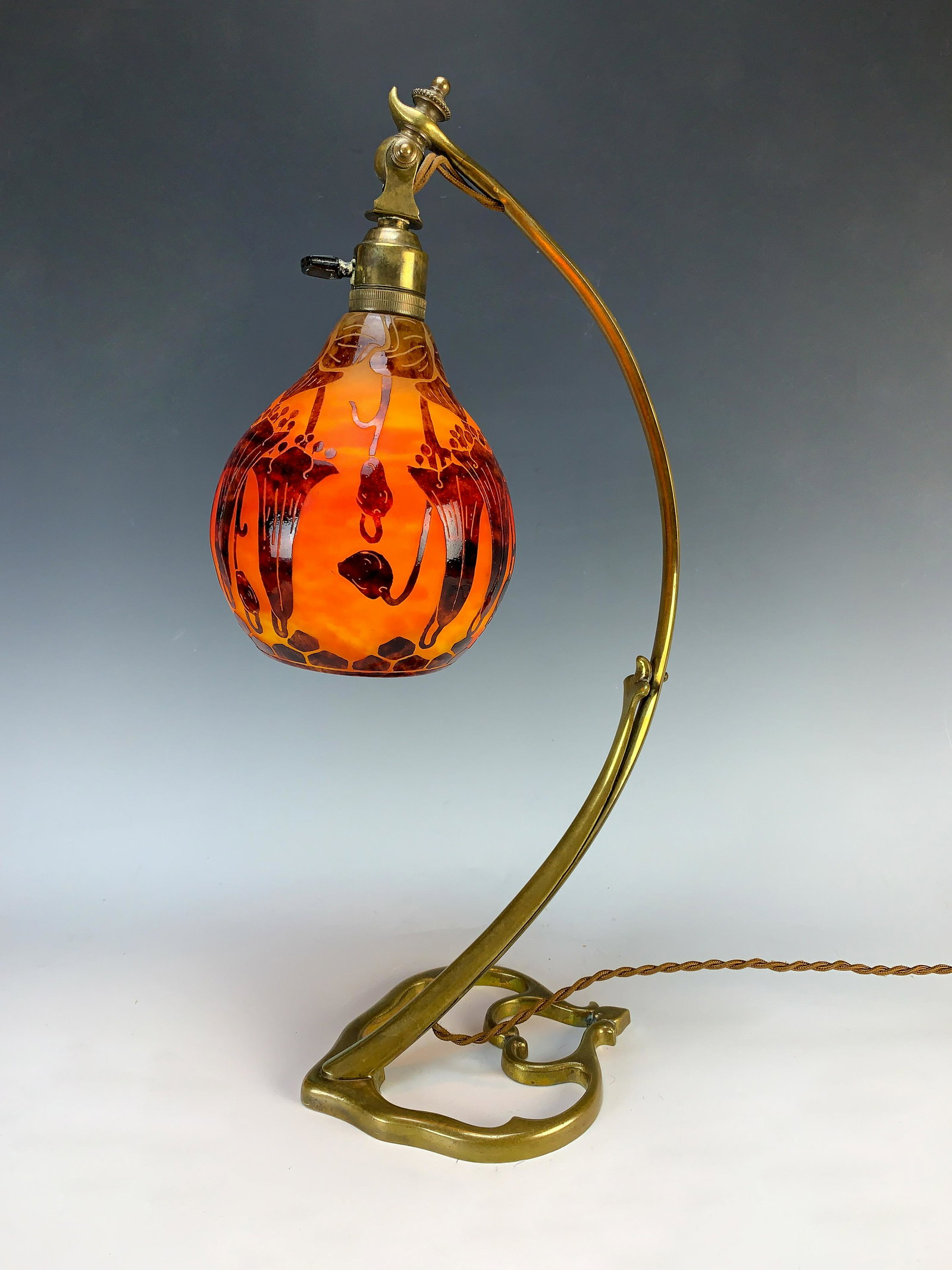 LeVerre Francais "Campanules" Cameo Glass Lamp: Circa 1920's, France. A teardrop shaped cameo glass shade with a dark brown campanules against a mottled orange ground. Unsigned. Shade mounted on its original bronze adjustable base. 18" tall. Condit