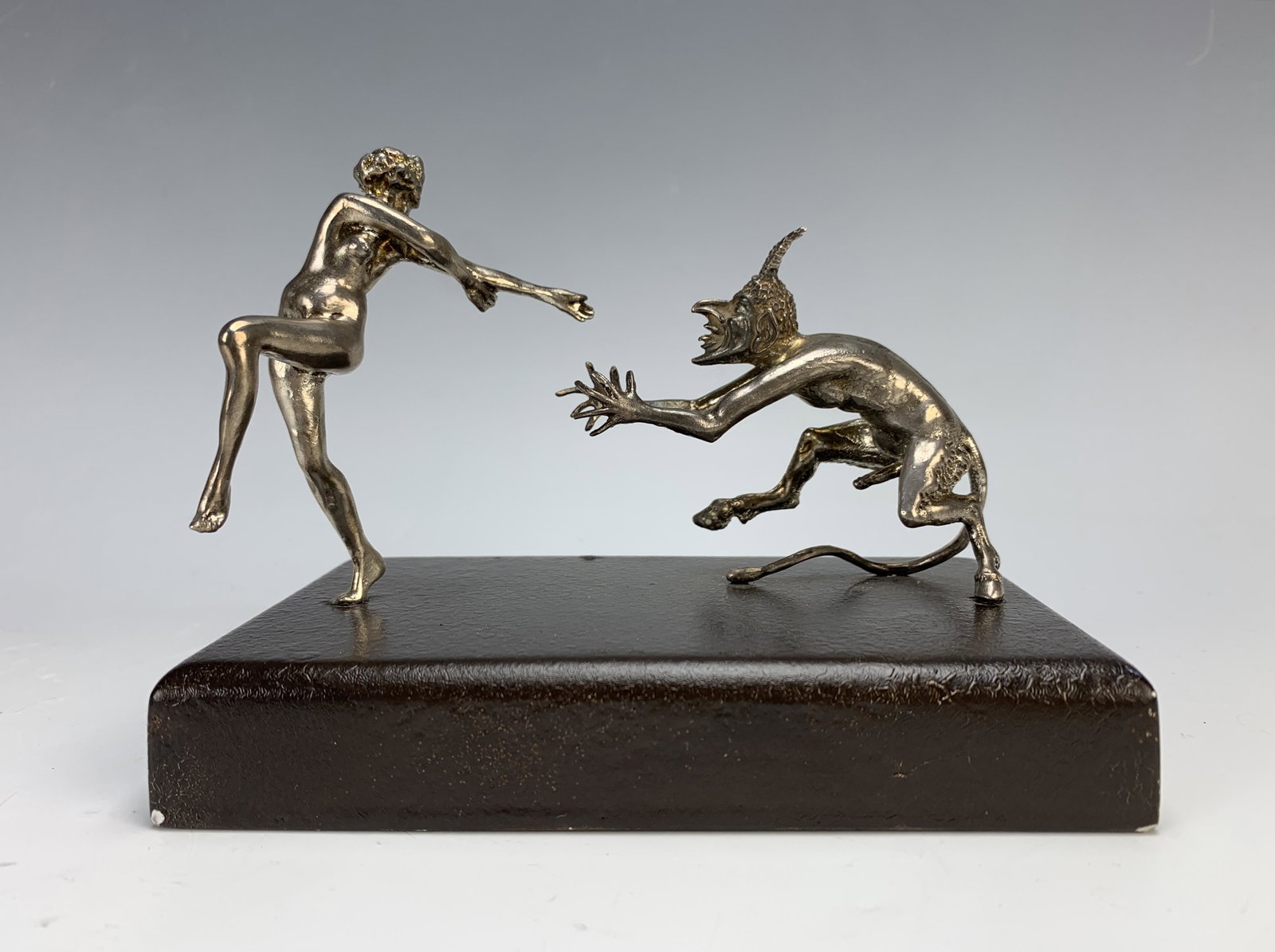 Sterling silver Devil & Lady Figurine: A humorous figure with a devil chasing a lady mounted on a painted black wood base, tested and guaranteed sterling silver, no marks, 5.5" x 4.25" x 3.5", very good condition. In-house shipping availab