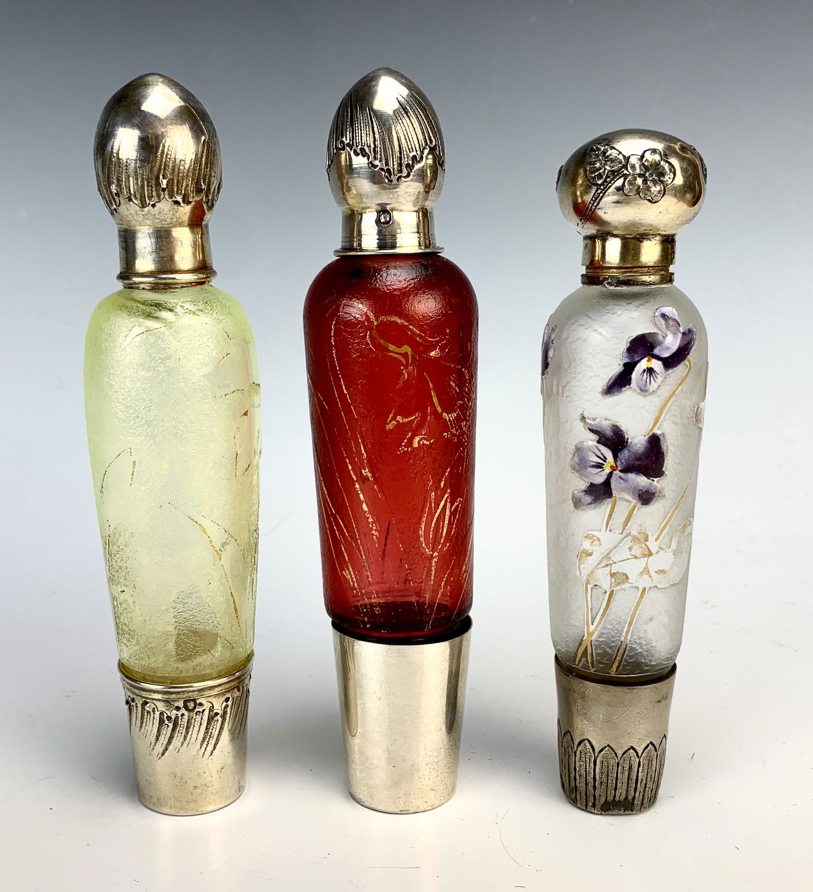 3 French Multilayered Cameo Art Glass Flasks: circa 1900, a red multilayered flask with sterling silver top and cup on bottom, a yellow multi layered flask with sterling top and cup on bottom, a clear frosted multi layered bottle with enamel viol
