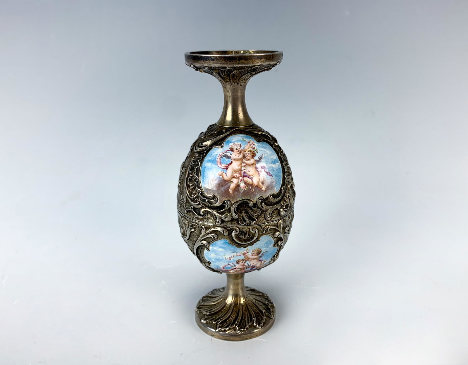 Rare Tiffany & Co Silver & Enamel Egg Cup: Late 19th century, Tiffany double egg cup with ornate silver work and four enamel medallions depicting cherubs in the clouds, twisting top off reveals two separate egg cups, signed "Tiffany & Co" and