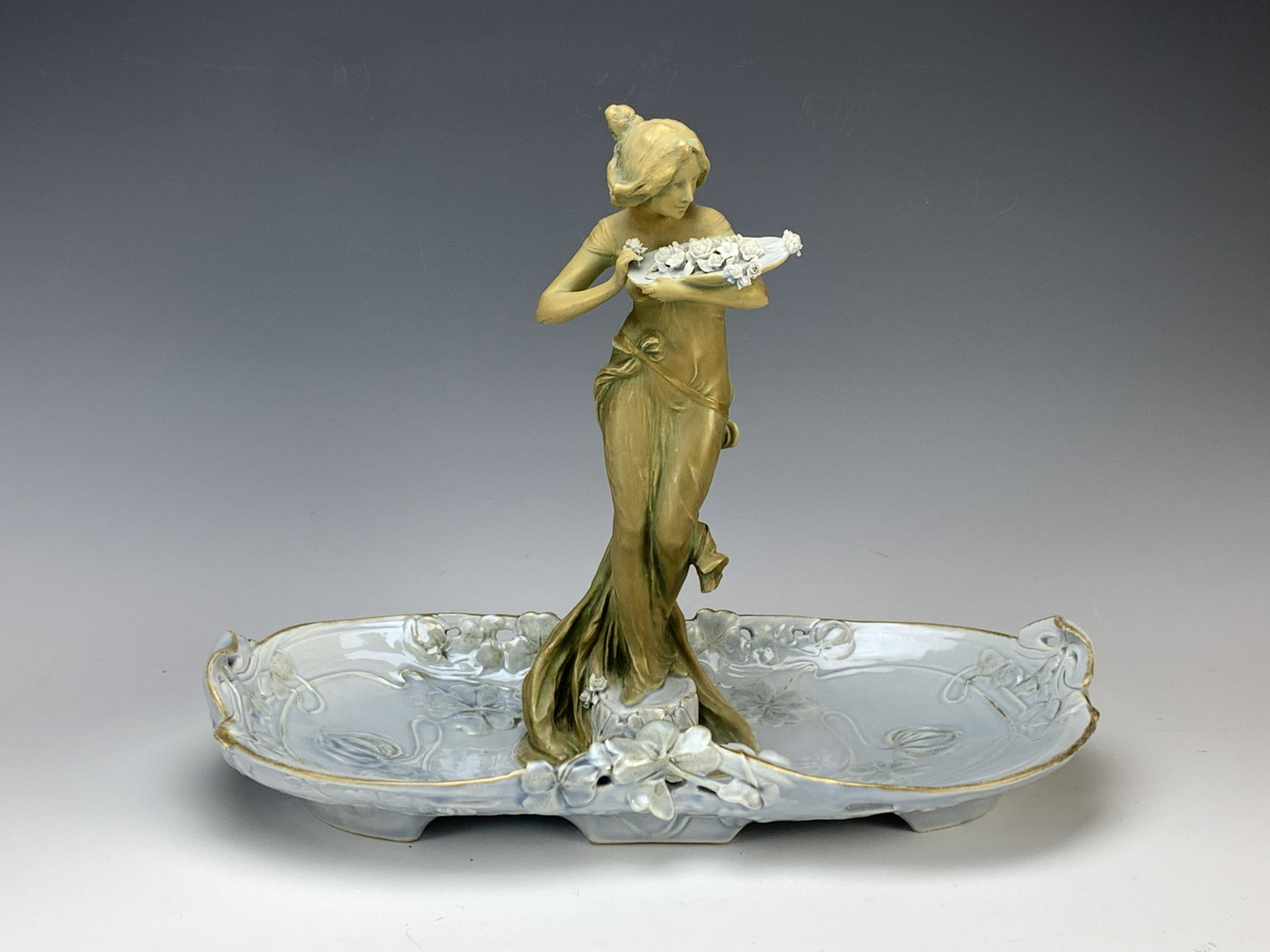 Ernst Wahliss Art Nouveau Lady Figural Tray: Circa 1900, made in Austria, a porcelain female figurine with a tray of flowers on a tray, signed with Ernst Wahliss blue crown mark, good condition, 15" wide. Have a similar item to sell? Email us at