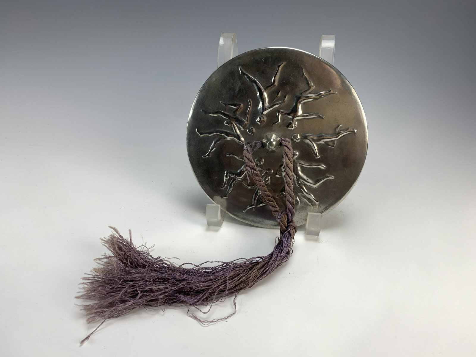 Art Nouveau Pewter Hand Mirror: A beveled circular pewter hand mirror decorated with dancing nudes, signed with raised monogram "CR" "H.B. Bergman Fud". Have a similar item to sell? Email us at info@treasureseekerauction.com