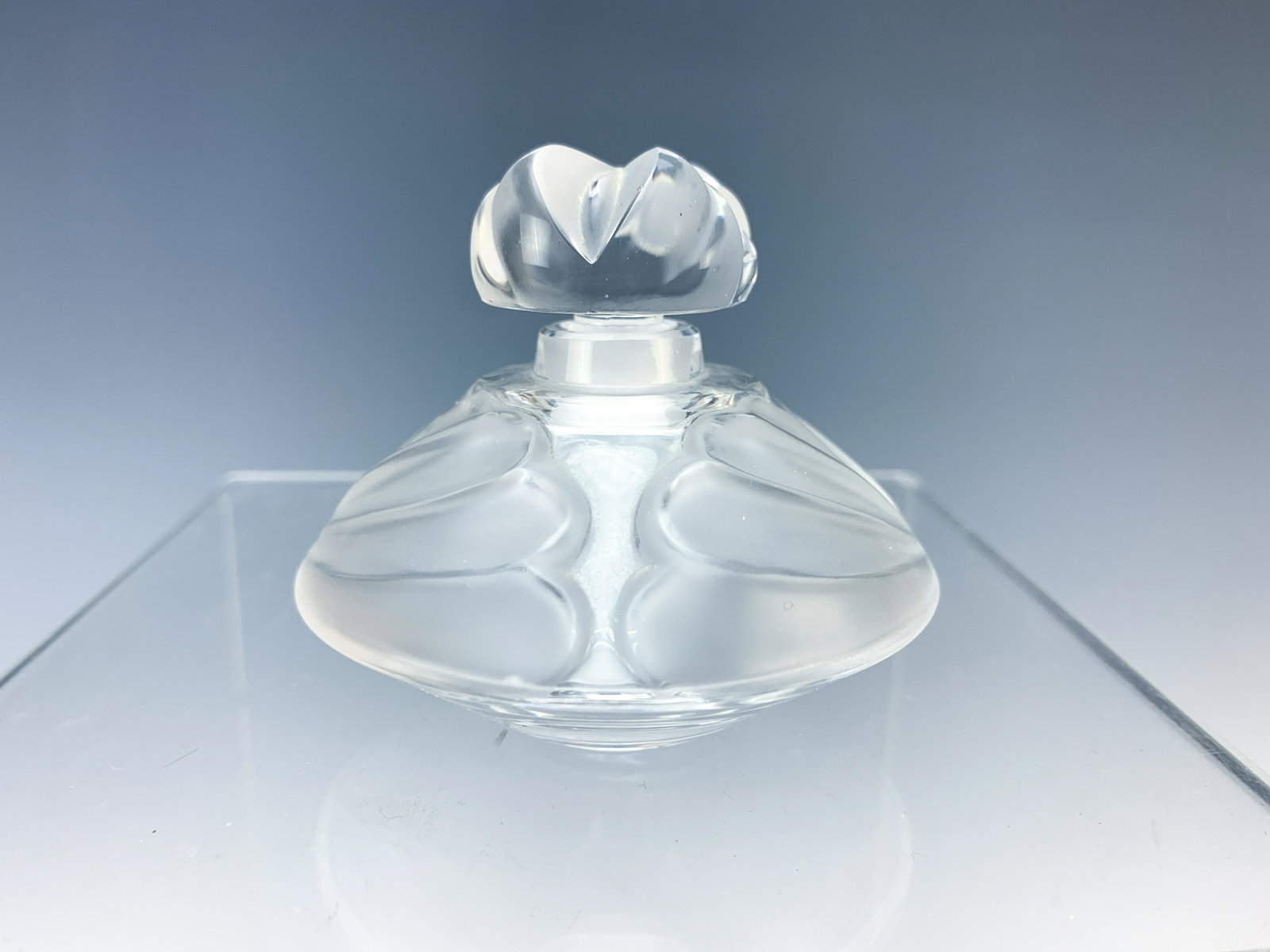 Lalique "Thais" (The Beloved) Perfume Bottle: Bottle measures 2 1/2" high x 2 3/4" in diameter and weighs 142 grams. lt is signed on the bottom. Product# 1131800. Retired at $460. Condition is like new.