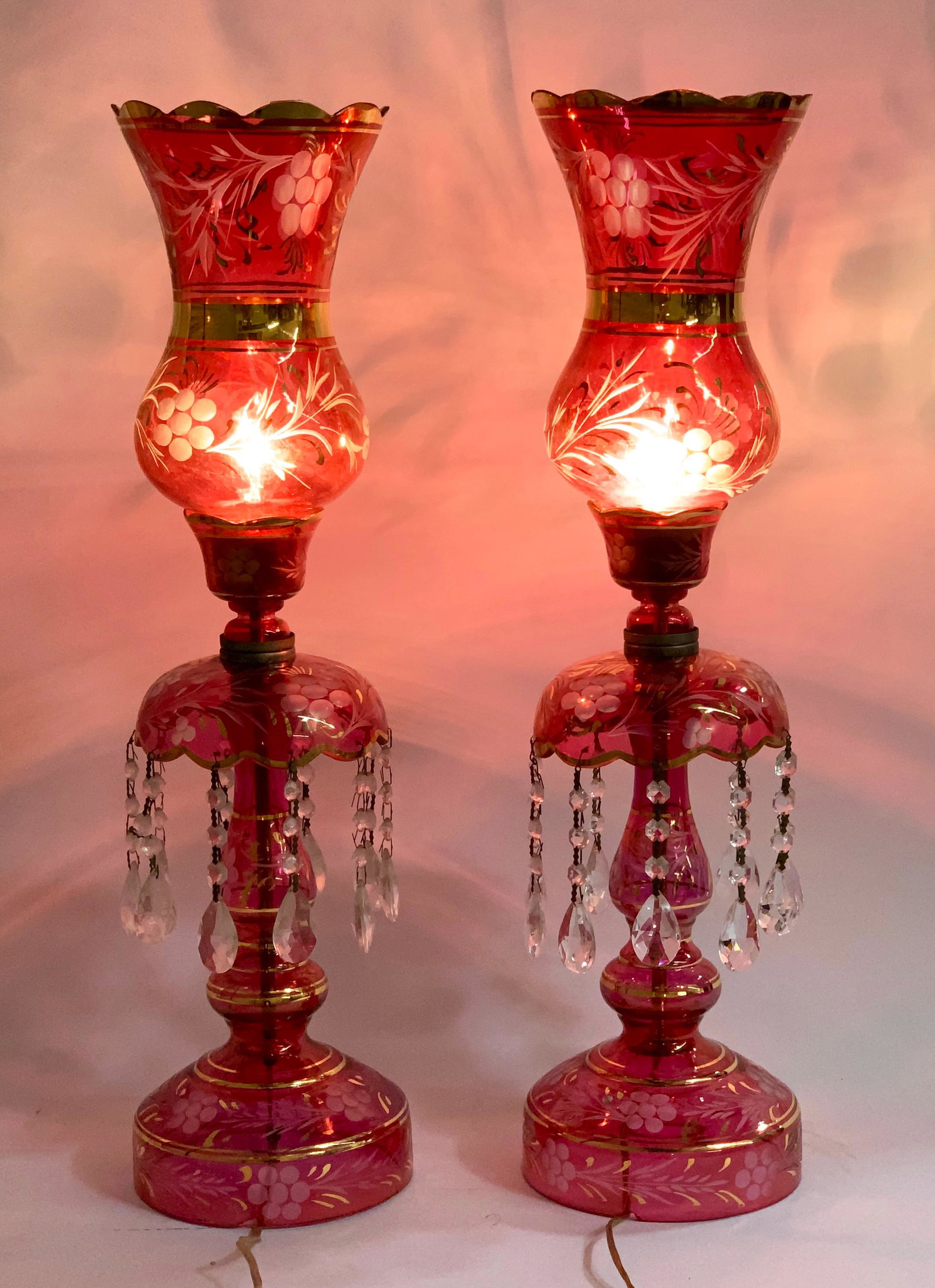 Large Pair Bohemian Persian Lustre Lamps: Stunning pair of cranberry Bohemian lustre lamps for the Persian market, each having cranberry glass bodies with carved clear flowers with gold gilt trim, metal lamp part is stamped "Iran", very good 
