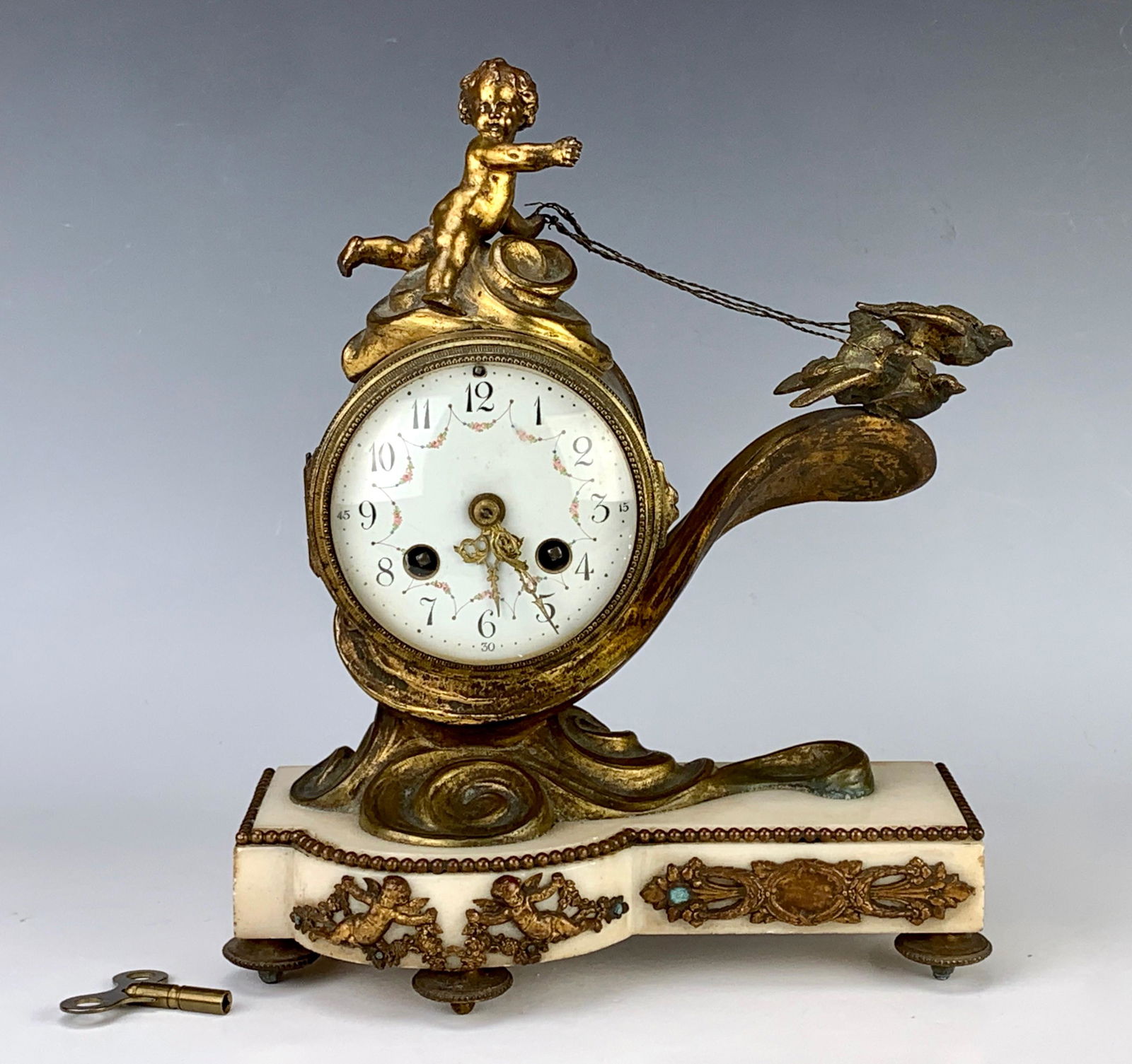 Louis XV Style French Clock "Putti & 3 Birds": Late 19th century, bronze clock depicting 3 love birds on a rein being held by a putti, also 2 cherubs decorating a white alabaster base, French movement, running at time of sale, oxidation wear comme