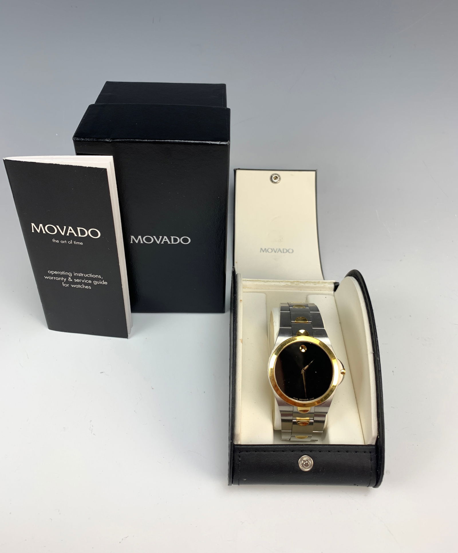 Movado Man's Quartz Wristwatch With Box: A man's Movado stainless steel and golden trim quartz movement wristwatch and bracelet. Case # 81E7/850. Comes with original box, papers, and one extra link. Leather case. Dial size: 1 3/8". Fits a ma