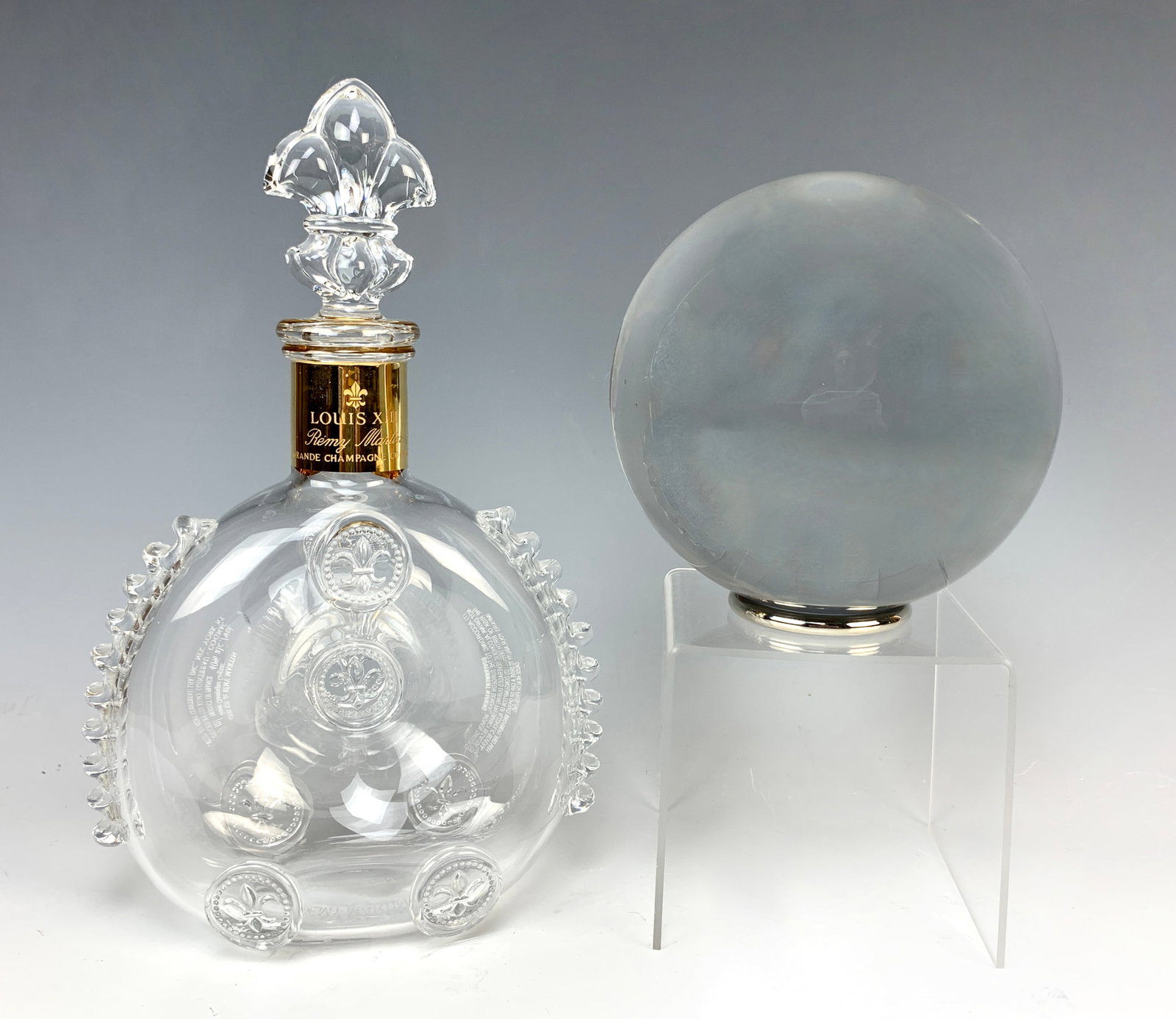 Baccarat Sirius Crystal Ball&Remy Martin Decanter: This lot consists of two items. We are serious about this Sirius crystal ball, the largest made. It measures 6 inches and weighs 12 pounds, and it comes with a metal ring stand. It is currently in pro