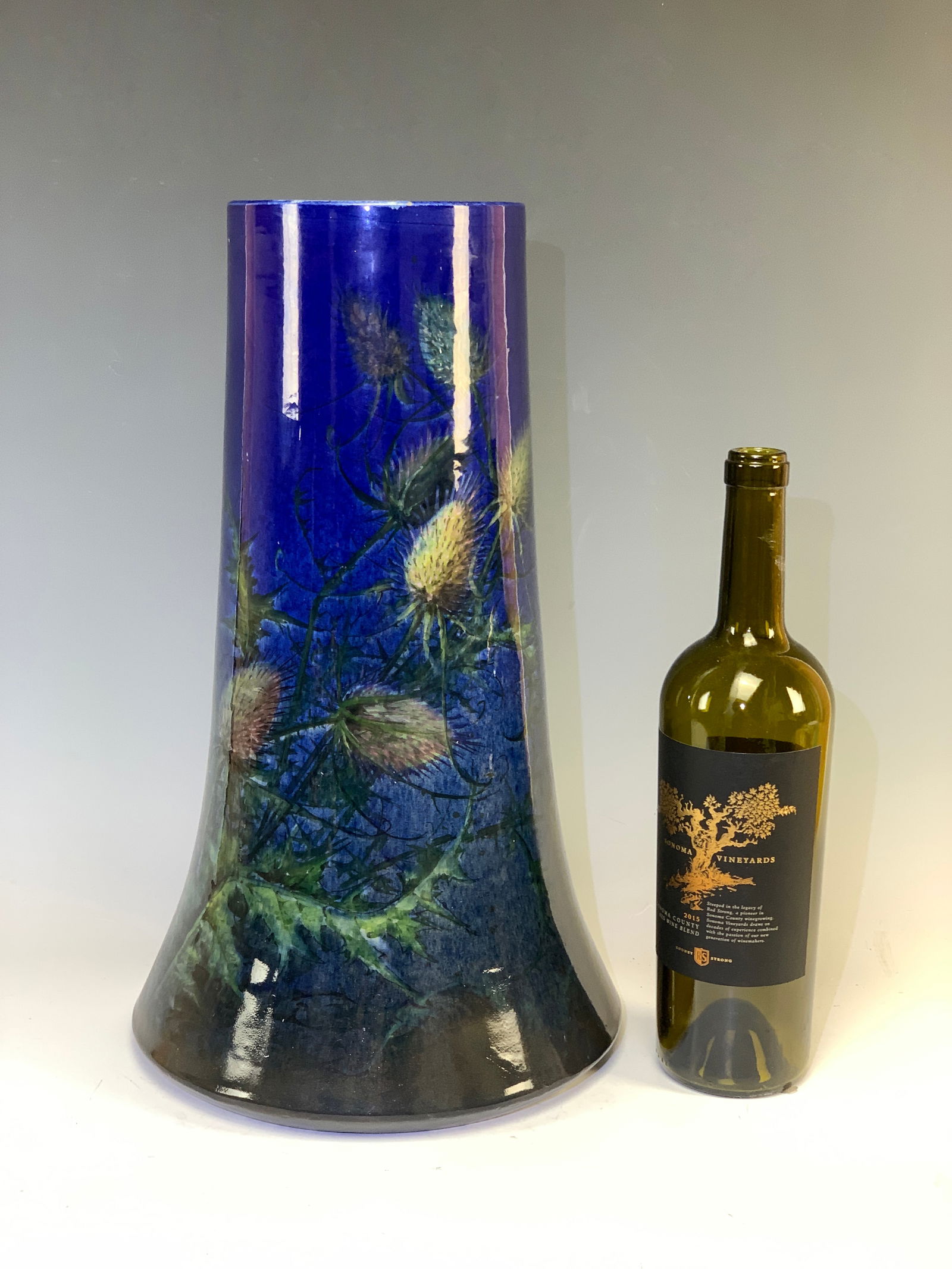 Clement Massier (1845-1917) Thistles Pottery Vase: Large pottery vase by Clement Massier, Golfe Juan, France. Beautiful curved tubular vase in polychrome enameled earthenware decorated with thistles against a blue background. Signed on the bottom "Cle