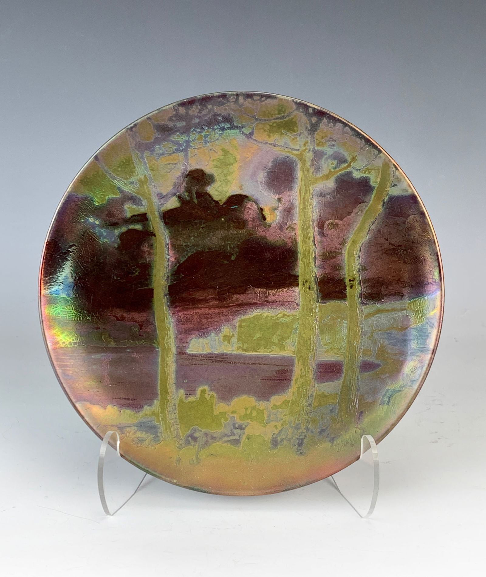 Clement Massier (1844-1917) Scenic Iridescent Plat: Circular iridescent ceramic plate with green, gold and red colors. Depicting mountains, trees and a lake. Signed Clement Massier Golfe-Juan AM. Size: 8 1/8" diameter. Excellent condition.