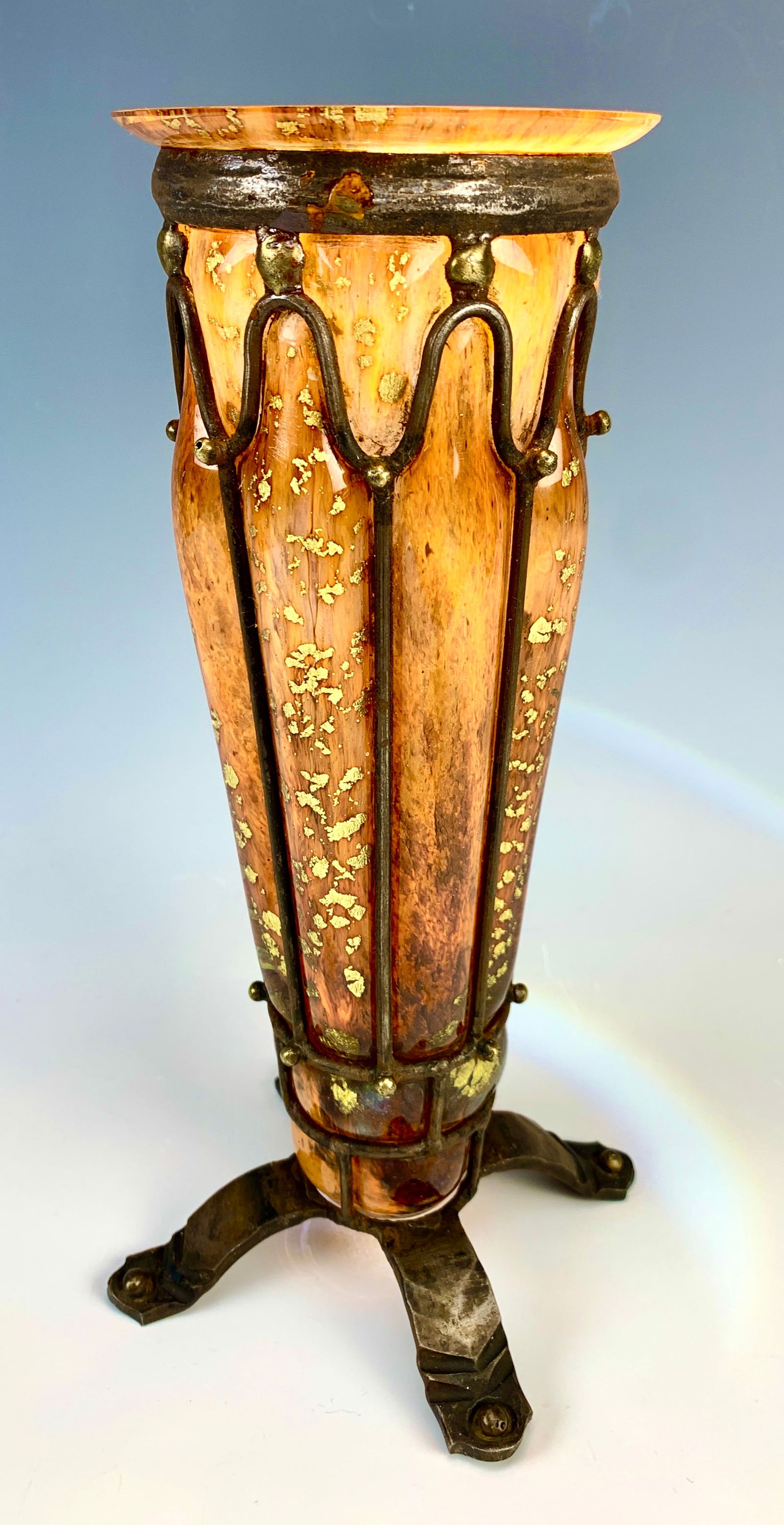 Daum & Majorelle (1859-1926) Glass + Iron Vase: Stunning signed Daum Nancy and Majorelle orange glass with gold foil flecks blown into an iron decorative frame. Resting on four rectangular iron feet. Size: 9.5" tall. Very good condition.