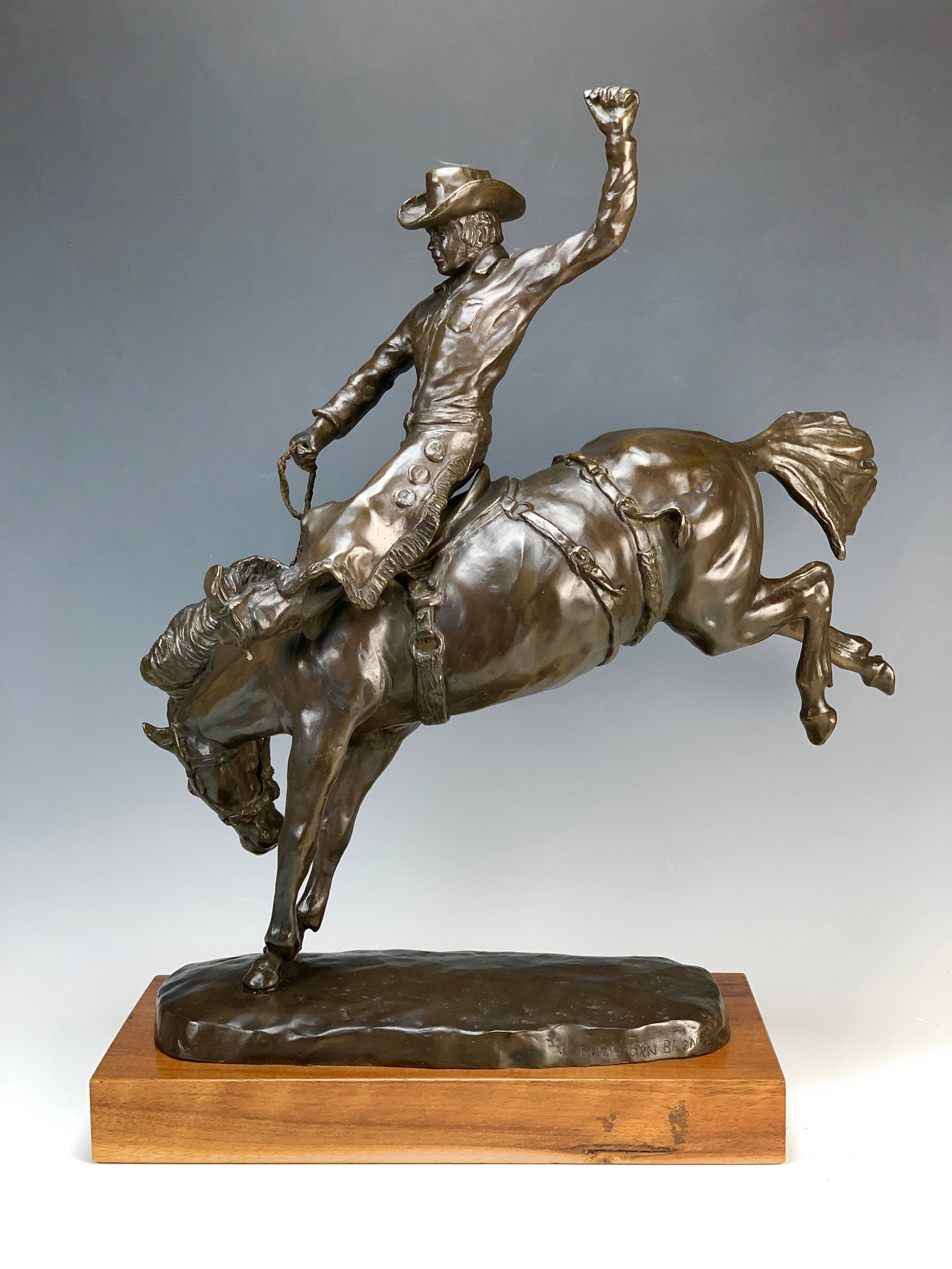 Tom Knapp (American, B 1925) Bronze Wyoming Cowboy: A bronze cowboy riding a bucking horse has long been the symbol of the state of Wyoming. Made by Buckhorn Foundries, it is mounted on a wood plinth and marked Tom Knapp and Buckhorn. Size: 21.5" with 