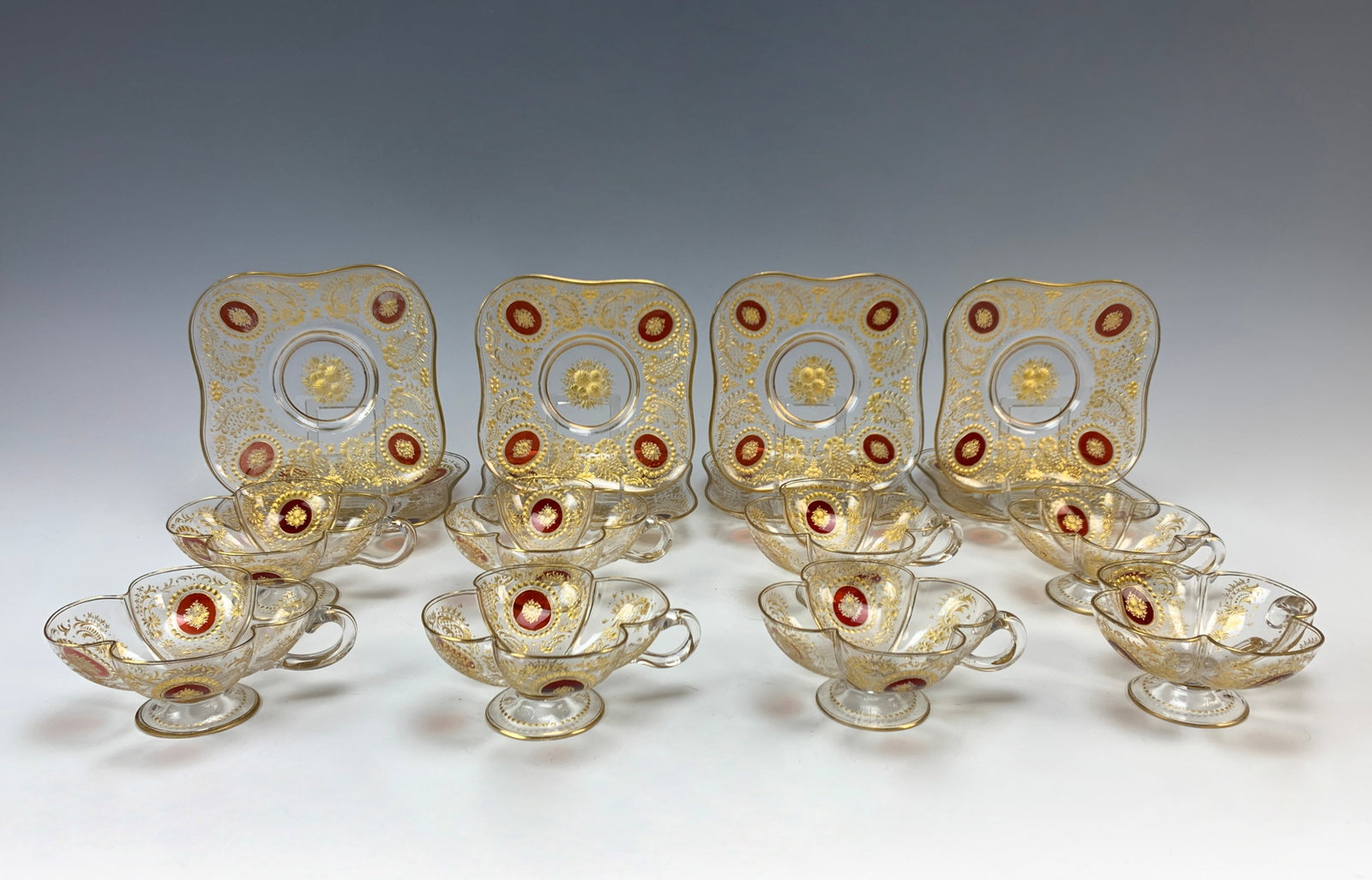 Set Of 8 Moser Enameled&Etched Glass Cups&Saucers: Circa: 1880. Set of 8 cups and saucers, 16 total. Cups are four-lobed shaped with gilt etching and four red enamel oval motifs. Saucers are square and unsigned, shaped with matching decorations. Size: