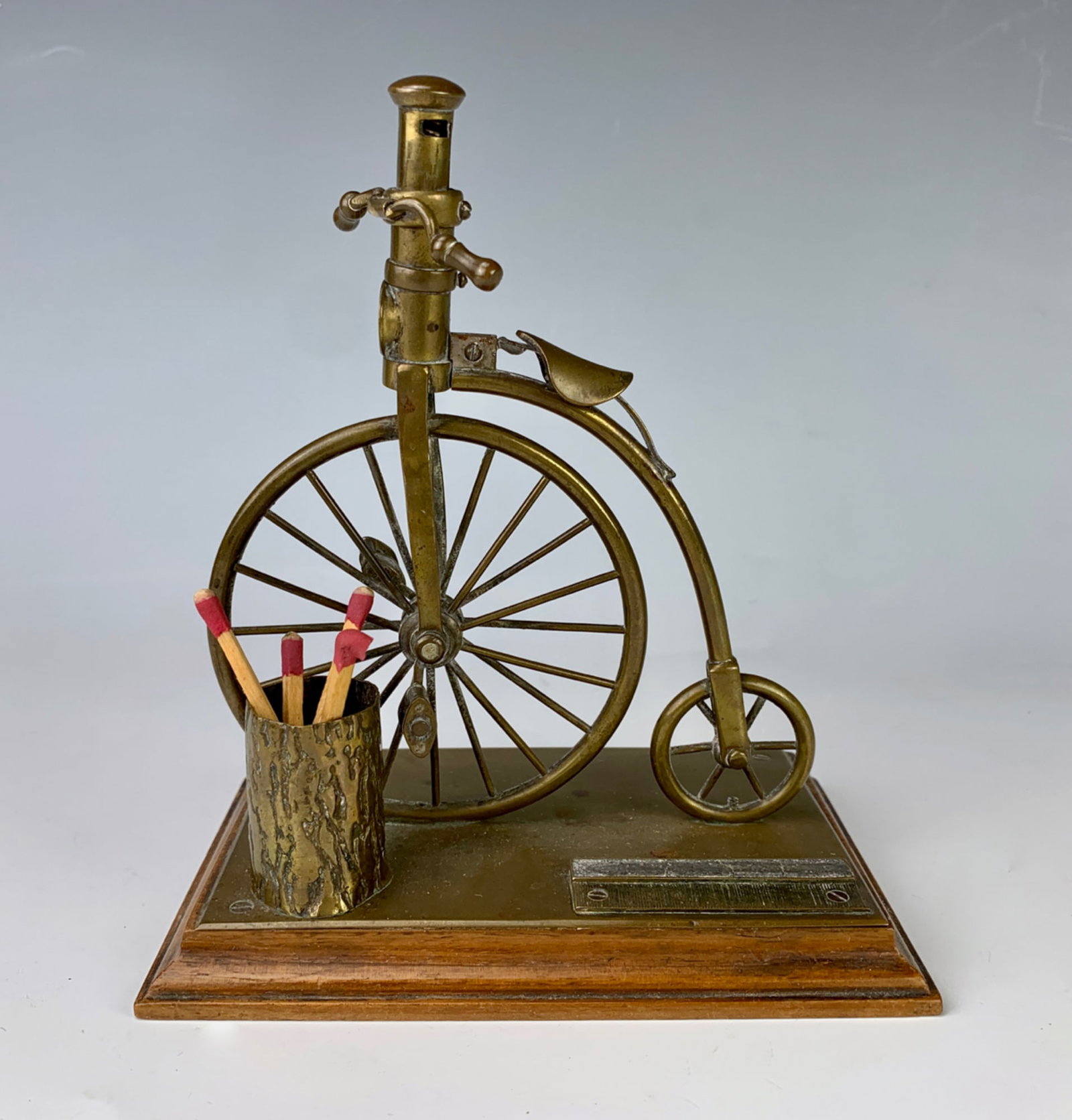 Rare High Wheel Bicycle Cigar Cutter Match Safe: Circa 1880, old fashioned bicycle cigar cutter, metal mounted onto a wooden base having a receptacle for matches and mounted with a striker, very good condition, 6" height *Domestic in-house shipping 