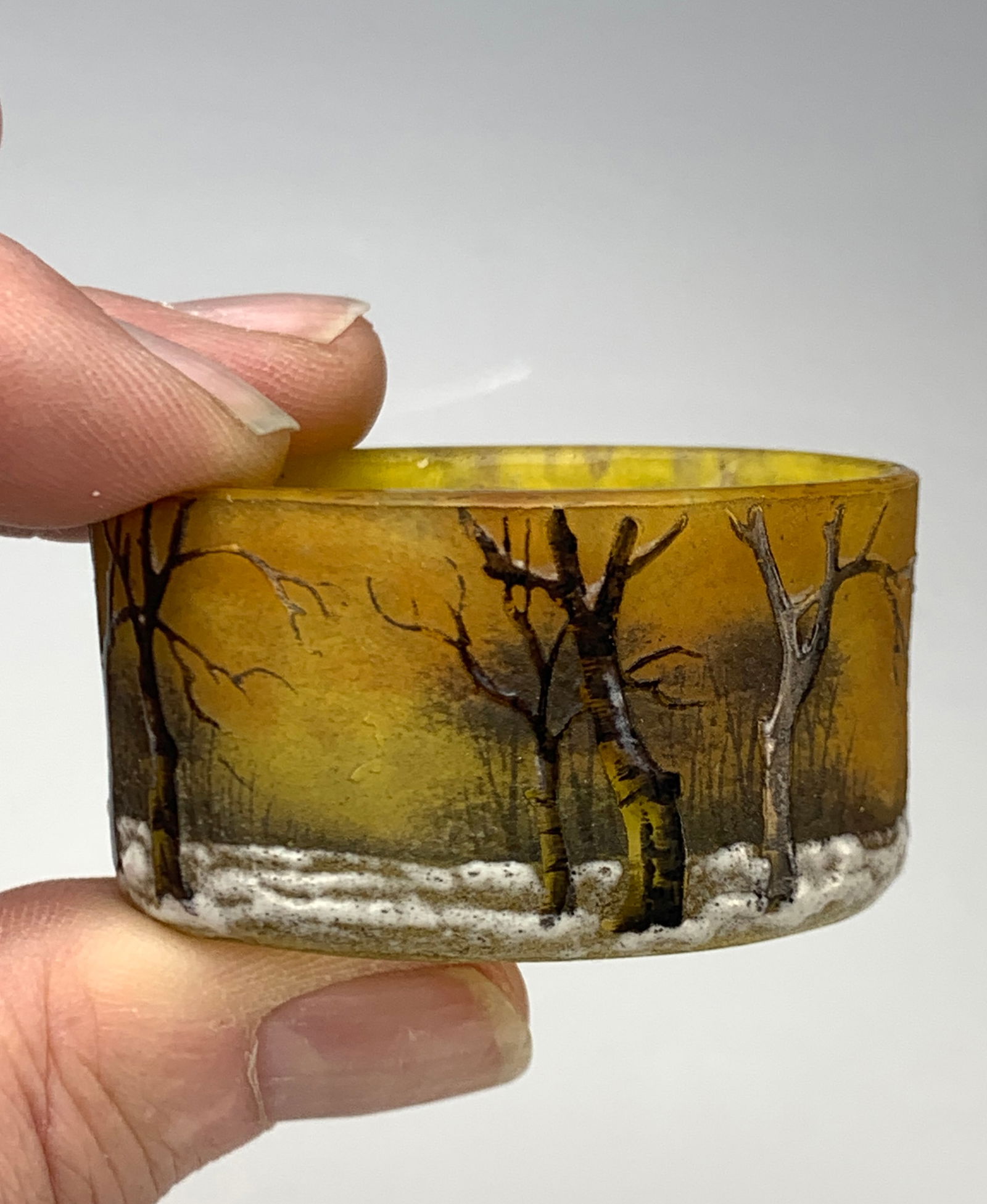 Daum Nancy Miniature Salt With Winter Scene: Nice Daum Nancy salt in a winter scene, signed on the bottom "Daum Nancy." Yellow ground with trees lined around the sides and snow on the ground. Condition: Very good.
