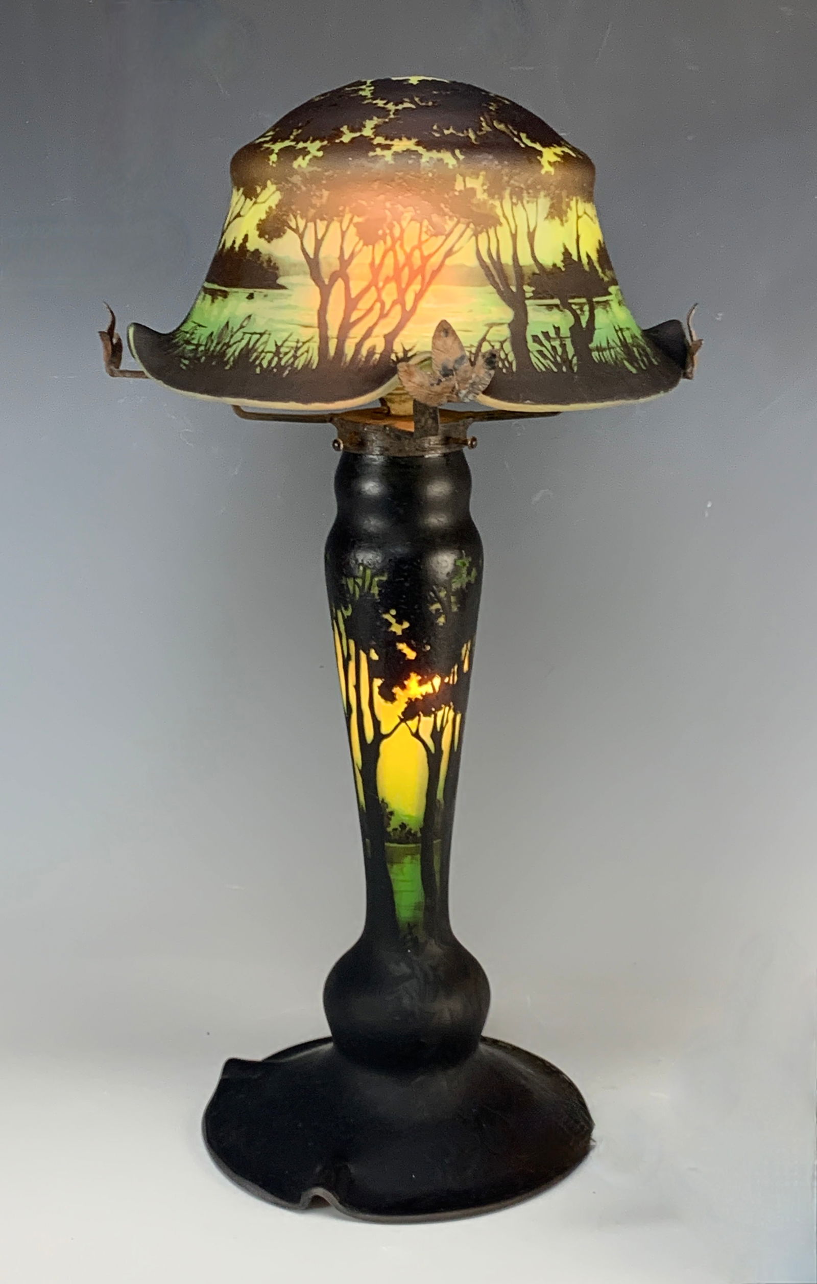 Daum Nancy French Scenic Cameo Lamp: Daum Nancy cameo lamp with the base and the shade in yellow, green, and dark green colors. Depicting a scenic shade with trees, mountains in the distance, and a lake. Bottom matches. Signed in cameo o