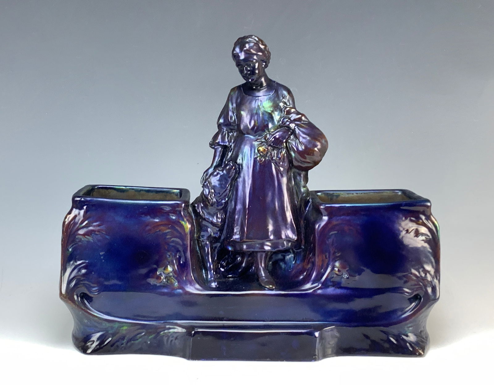 Zsolnay Attrb "Lady And Her Dog" Large Double Vase: Circa 1900. Unsigned, attributed to Zsolnay. Featuring a woman peasant with her dog at her side between two vases. Made of ceramic with an iridescence in dark blue. Art Nouveau design. Size: 13.5" tal