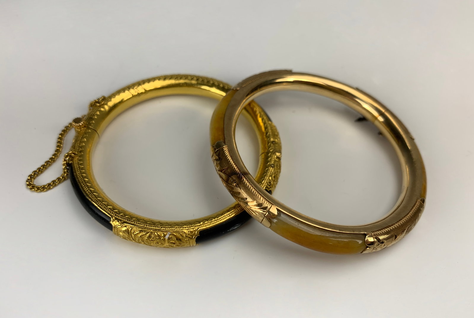 2 Asian 14K Gold Jade&Gemstone Bangle Bracelets: Set of 2 Asian 14K gold bangle hinged bracelets. One with a black hardstone, 55mm diameter of the inner circle, mark illegible. The other is a jade bracelet with a 57mm diameter, marked 14K. Condition