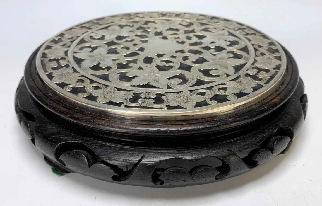 Glass/ Sterling Covered 'Trivet': Glass/Sterling Covered 'Trivet' attached to a Chinese carved wooden stand. Trivet size: 5 7/8" wide, and stand is 7" wide. Sterling marked 'Webster' on edge. Condition: Very Good.
