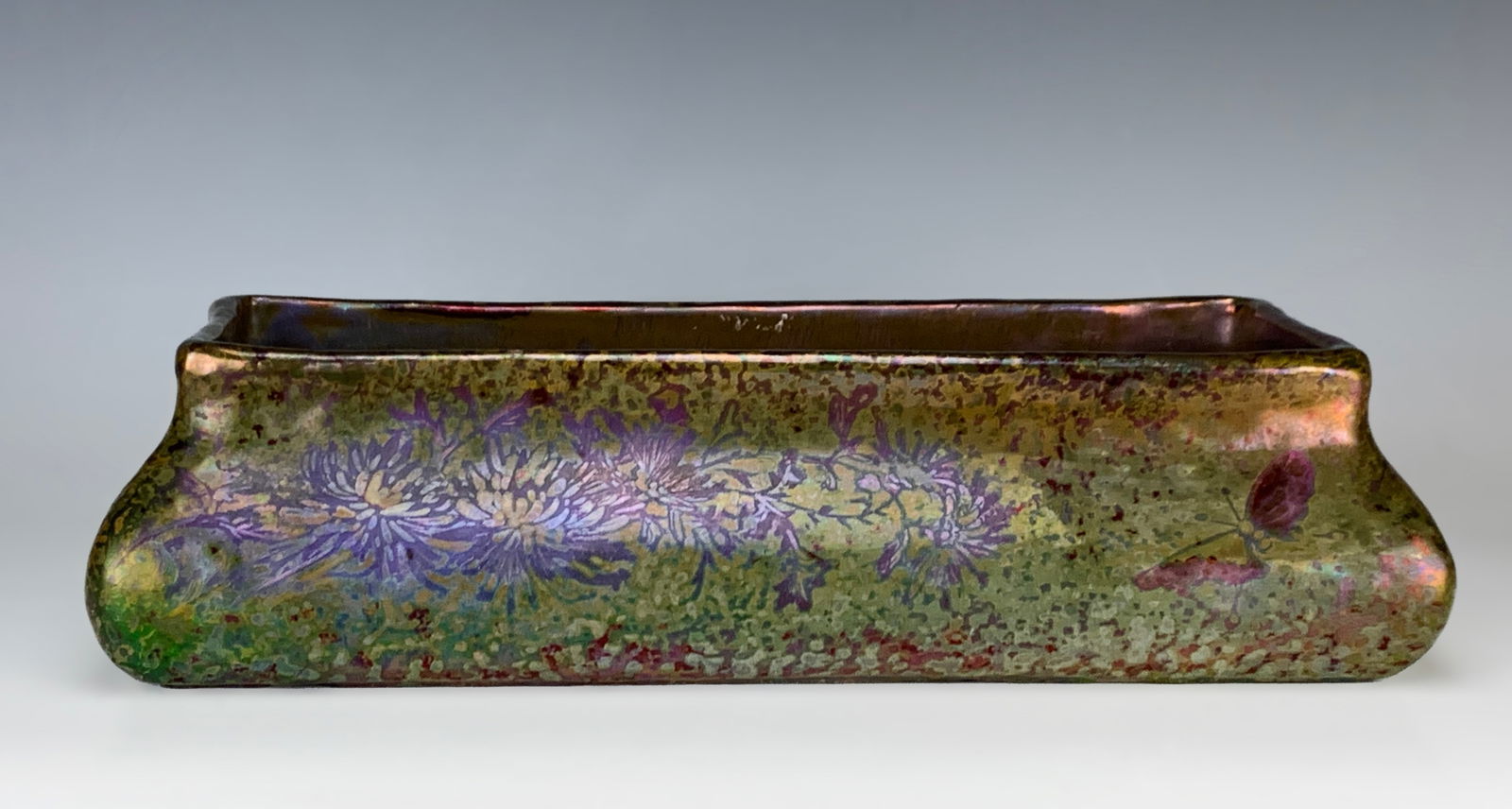 C. Massier (1845-1917) Jardiniere with Butterflies: Amazing signed Clement Massier iridescent metallic glaze jardiniere decorated with butterflies amongst a bed of flowers. Having a rectangular shape in gorgeous colors of greens, purples, it's rare to