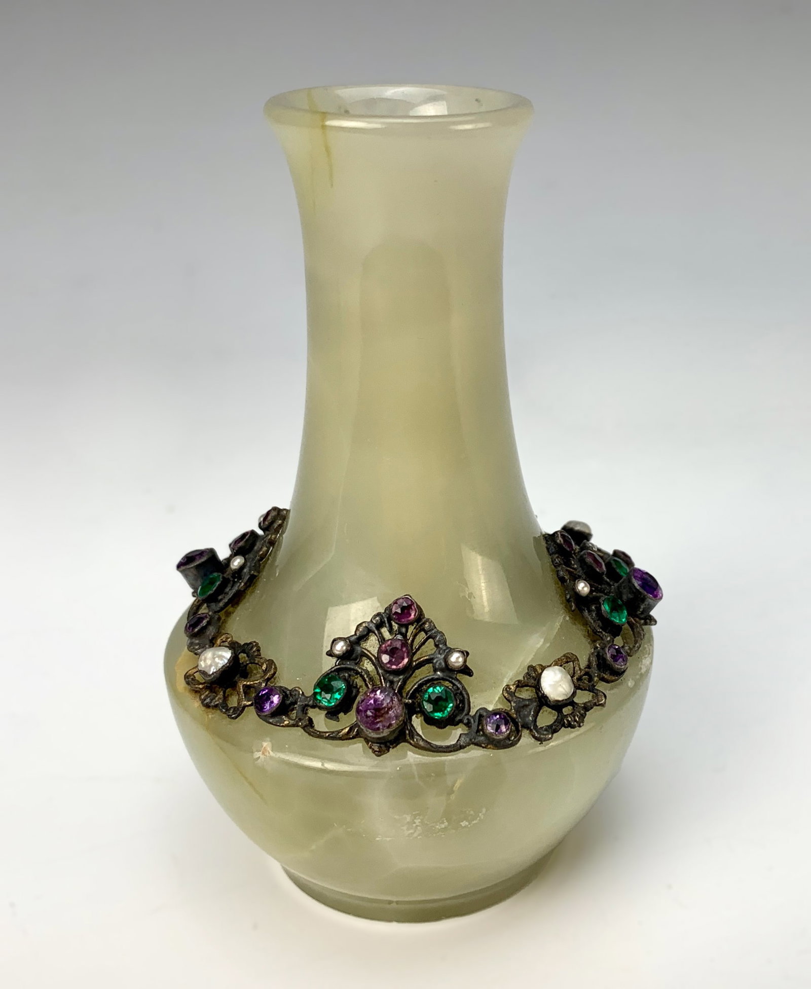 Carved Onyx Vase With Jewels: Circa 1900. Small onyx vase with a wider bottom tapering to a narrow cylindrical top, adorned with different colored jewels applied on a metal support. Size: 4" tall. Condition: Good.