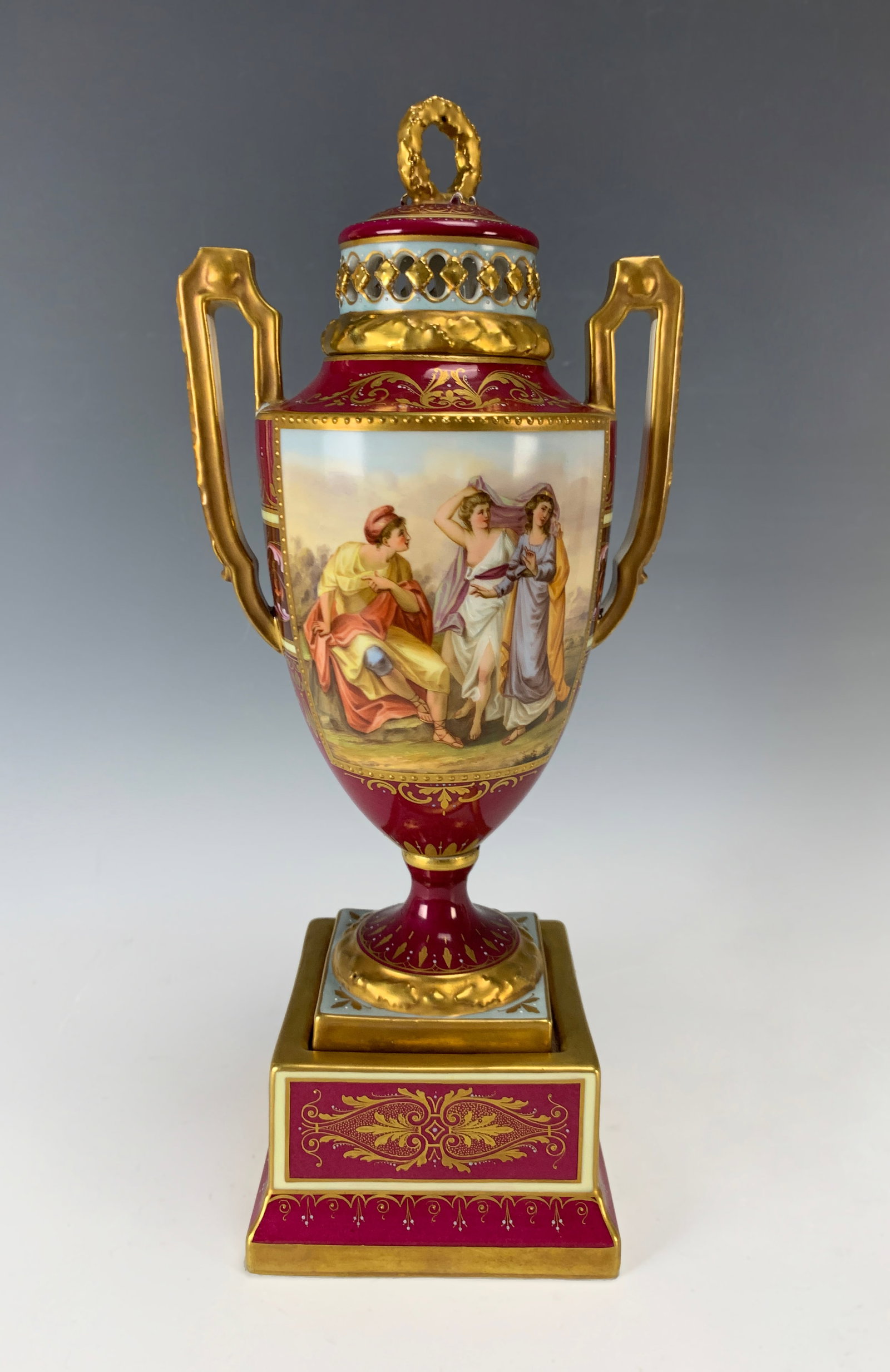 Royal Vienna Hand Painted Urn "Paris & Helena": Circa 1900. A large Sevres urn with two panels featuring hand-painted scenes of romantic couples. The rare panels have flowers painted against a red ground body. Gilt bronze handles with ram heads, ma