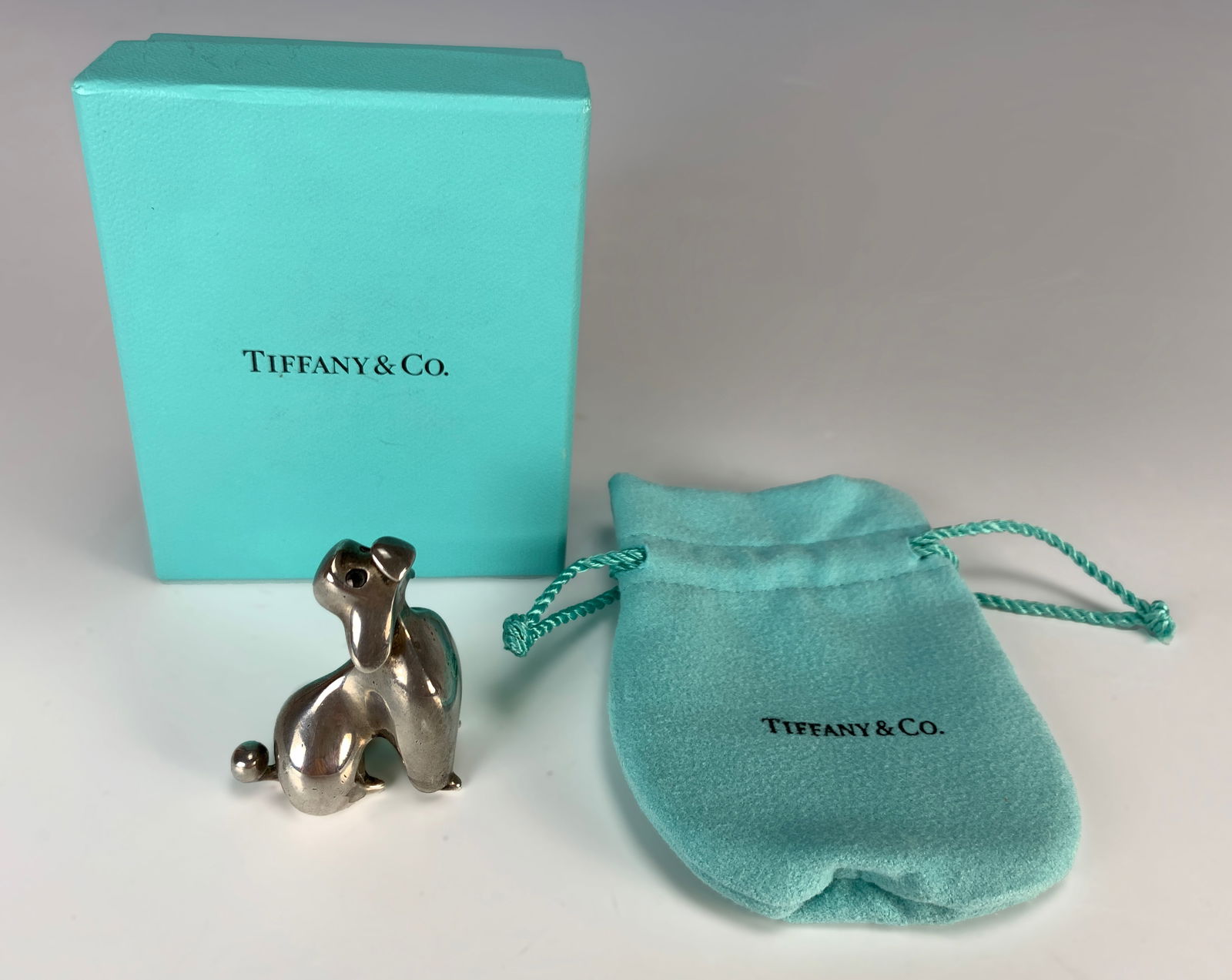 Tiffany & Co. Sterling Poodle Paperweight: Authentic Tiffany & Co. sterling silver poodle paperweight. Size: 1 7/8" tall. Weight: 86.5 grams. Comes with Tiffany & Co. pouch and box. Condition: Good.
