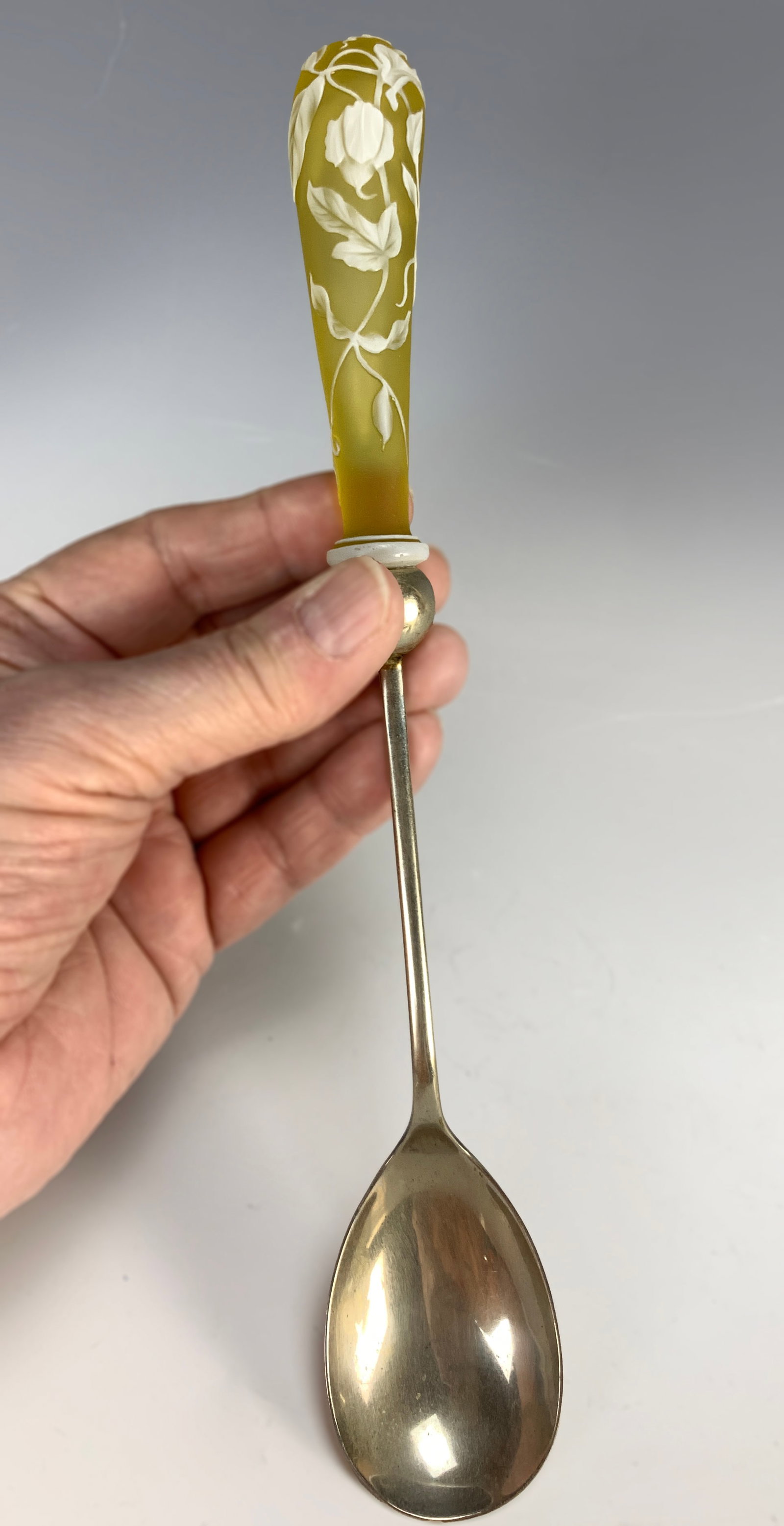 English Cameo Glass Spoon: English cameo glass spoon, with cameo decoration of white over yellow, featuring leaves and flowers. Silver-plated spoon marked "Made in England." Size: 10.5" long. Condition: very good.