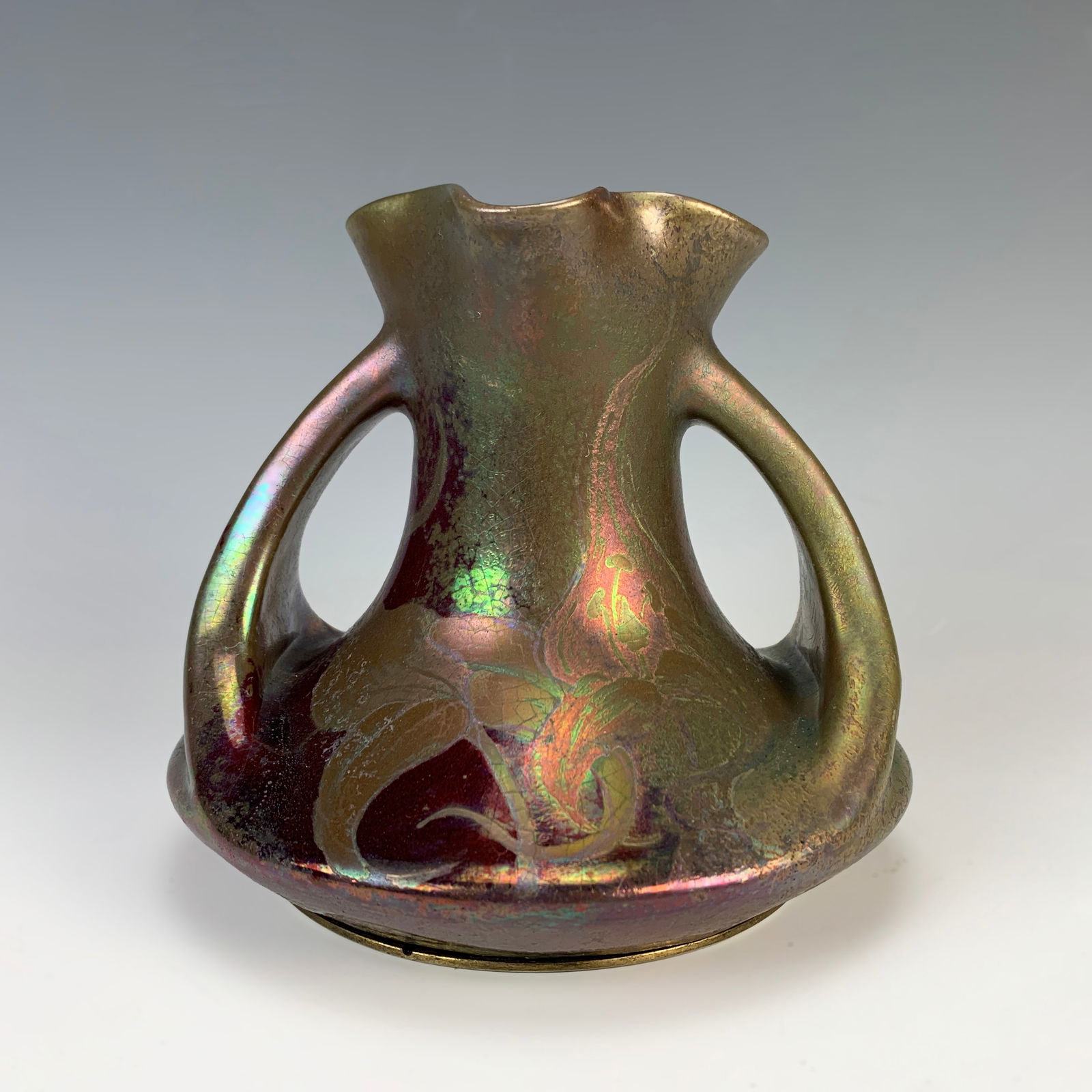 Clement Massier Iridescent Pottery Vase: Early 20th C. Signed Clement Massier, Golfe-Juan AM. Decorated with purple/silver over a ruby red body. Has a sterling silver round foot with French hallmarks. Size: 5.5" tall x 6.5" wide. Condition: